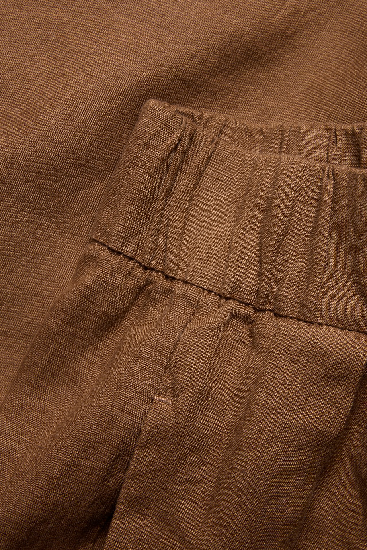 Närbild av bruna linneshorts med elastisk midja.