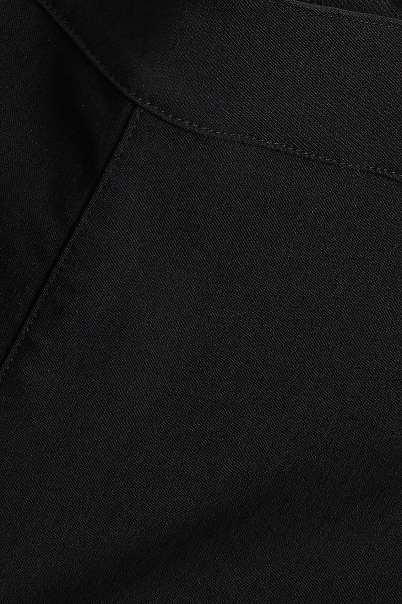 Zbliżenie na jednolity czarny materiał spodni capri z widocznymi szwami.