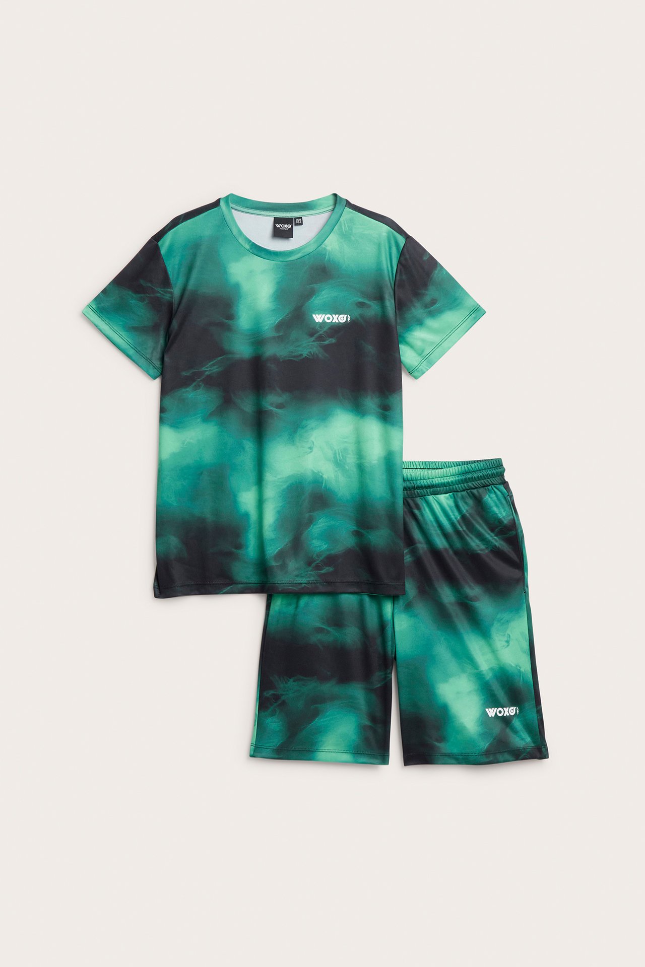 Framifrån, ett mörkgrönt och svart mönstrat sportset i polyester för barn med t-shirt och shorts.