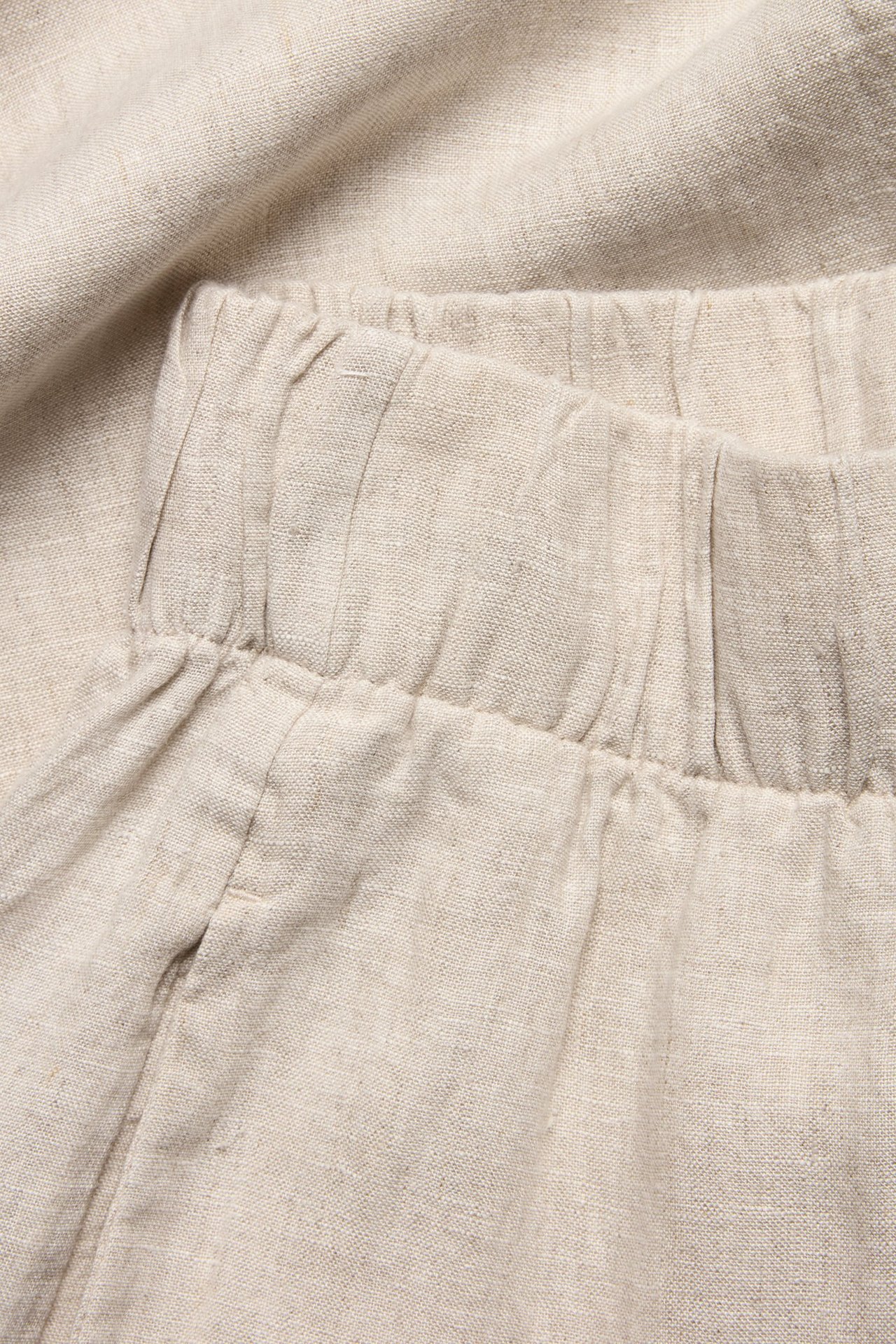 Zbliżenie beżowych melanżowych lnianych spodni z elastyczną talią.