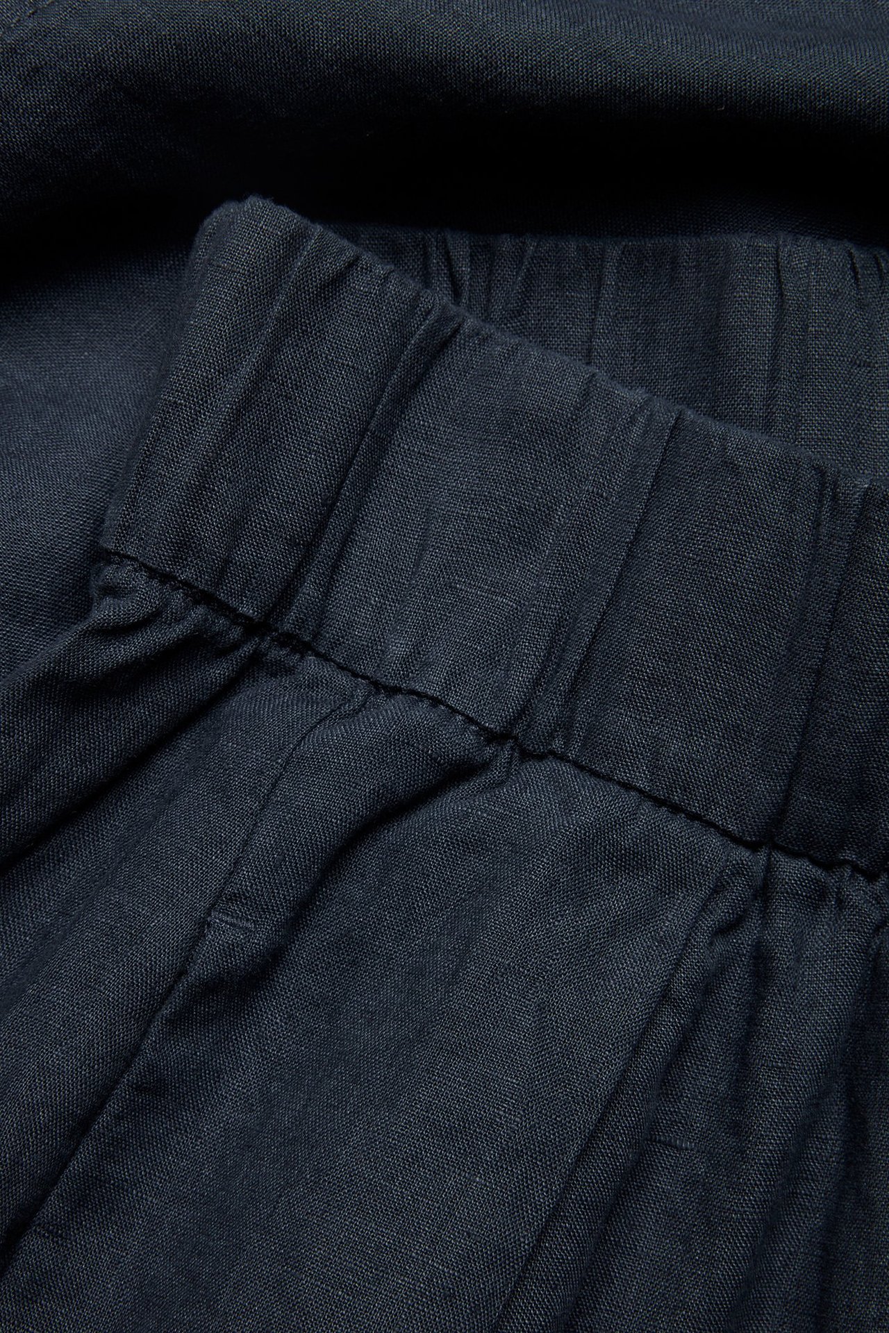 Zbliżenie na granatowe lniane spodnie pull-on z elastyczną talią.