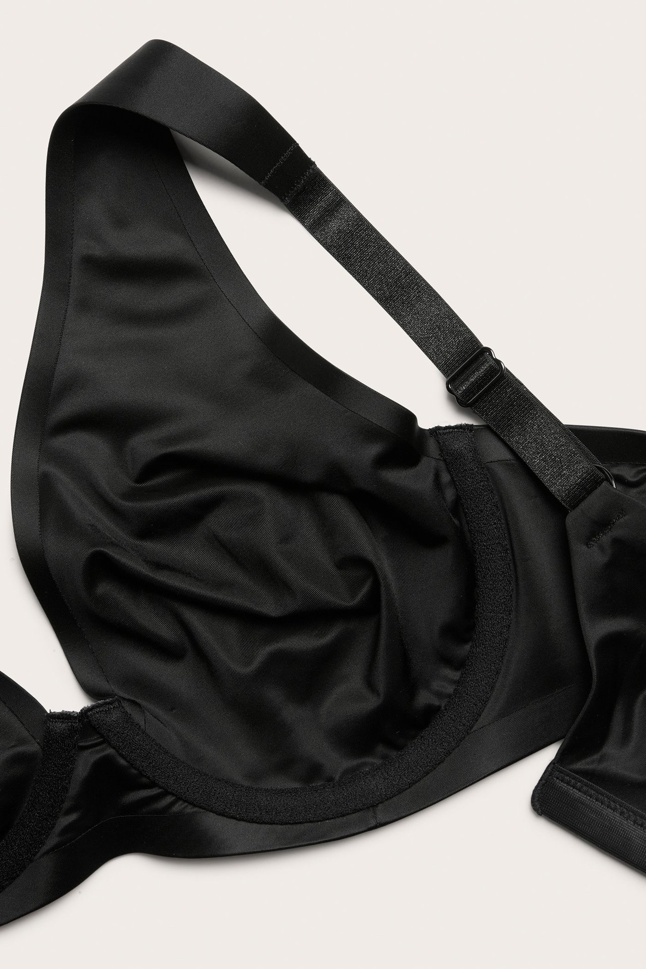 Zbliżenie czarnego biustonosza z fiszbinami z satynowej mikrofibry z szerokimi, regulowanymi ramiączkami.