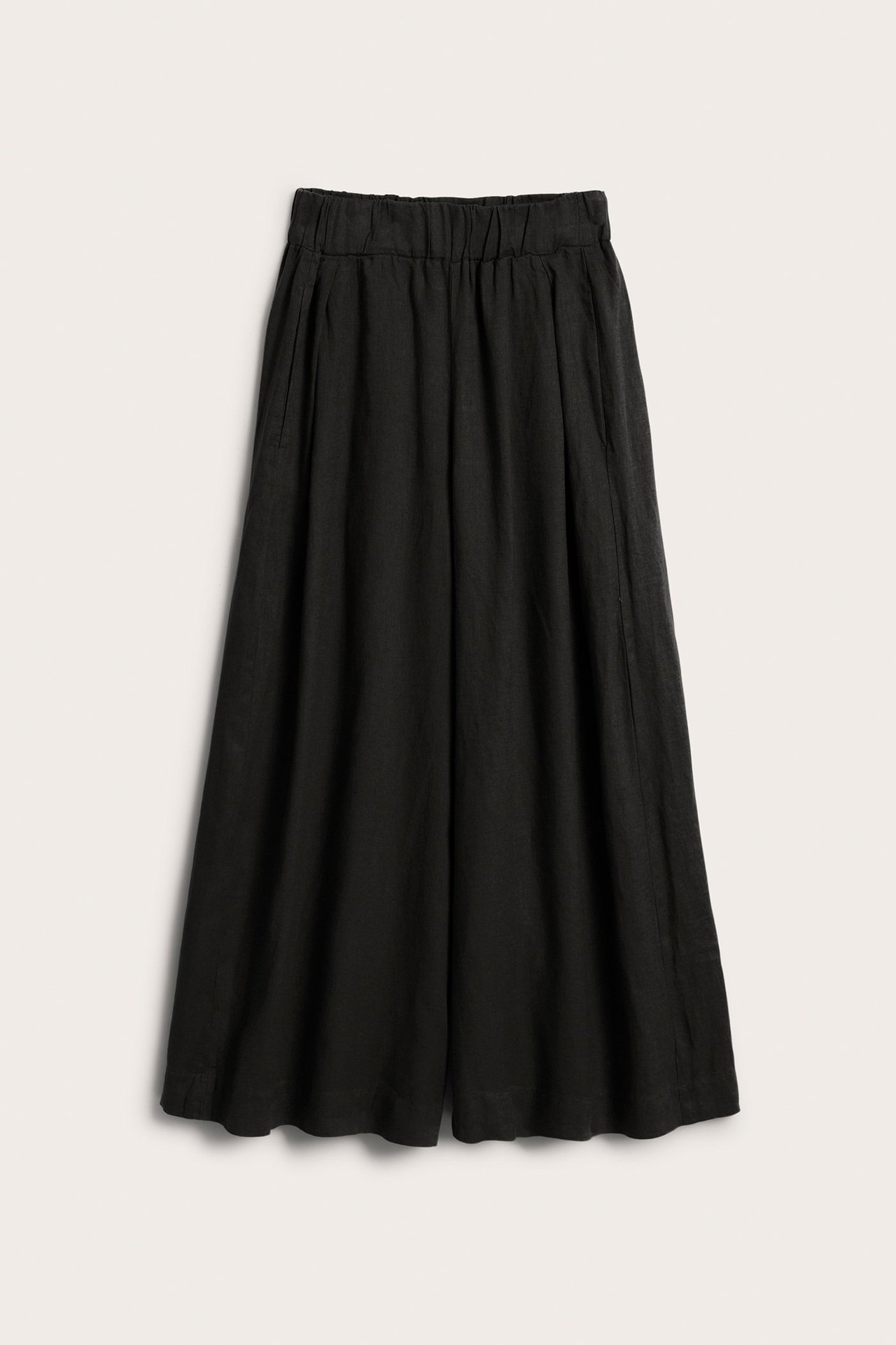 Edestä näkymä mustista pellavaisista leveälahkeisista housuista, joissa on joustava vyötärö ja sivutaskut.