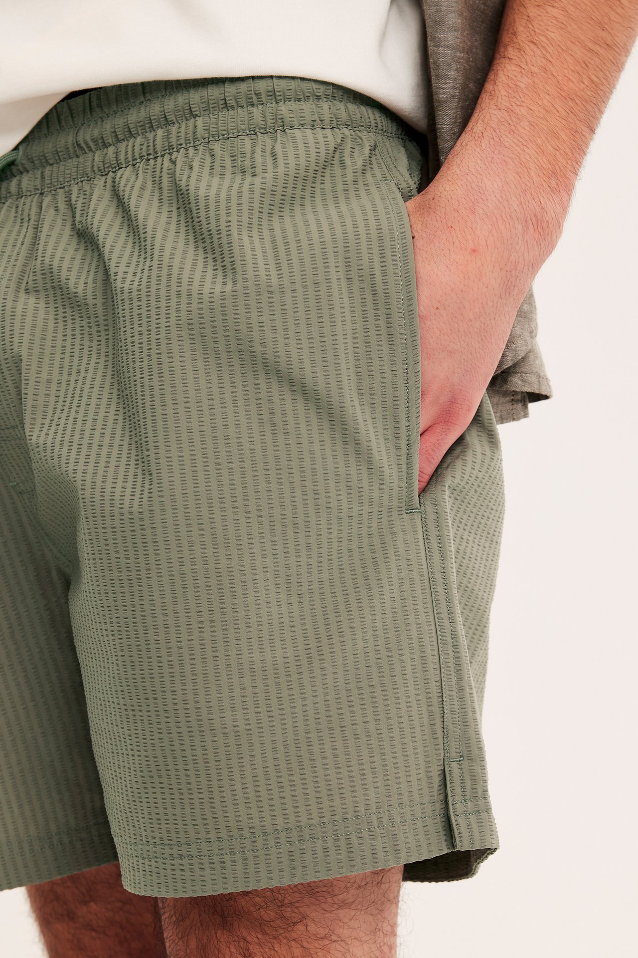 Herrbadshorts i grön struktur med resår i midjan och sidfickor, framifrån.