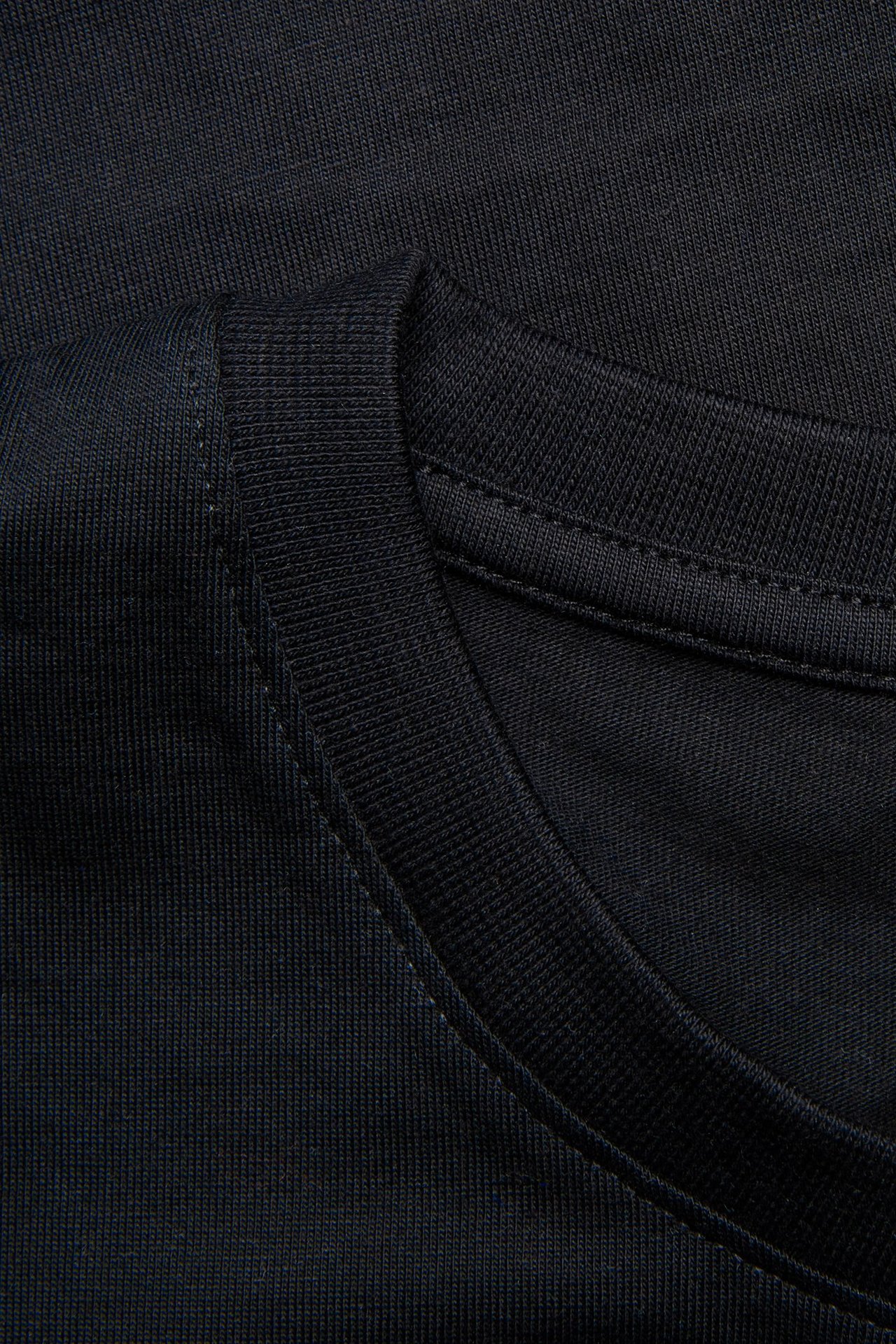 Zbliżenie na męski, granatowy, jednokolorowy t-shirt z okrągłym dekoltem ze 100% bawełny.