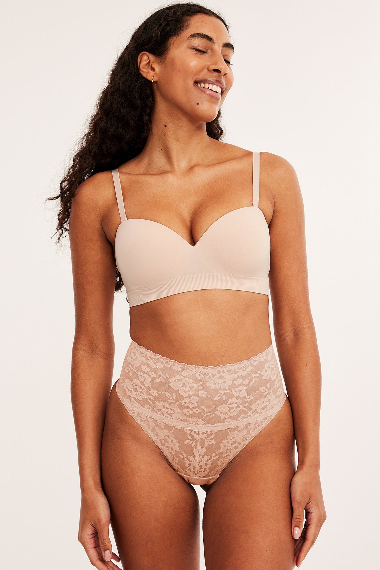 Frontbilde av kvinne i lys rosa blonde-stringtruse med høy midje og shaping, samt lys rosa sømløs BH.