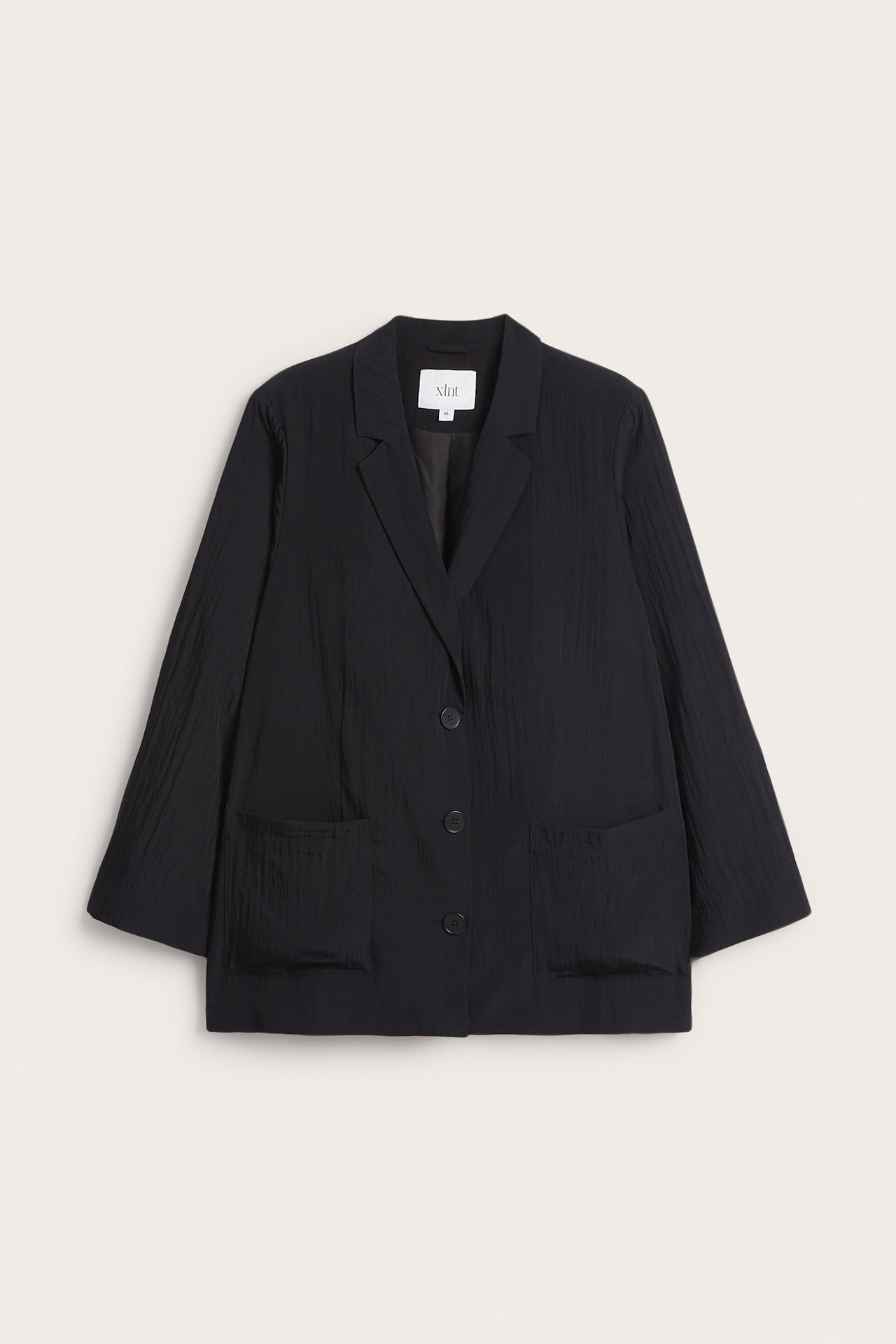 Frontvisning av en svart krøllet uforet blazer med slag, tre knapper og to påsydde lommer.