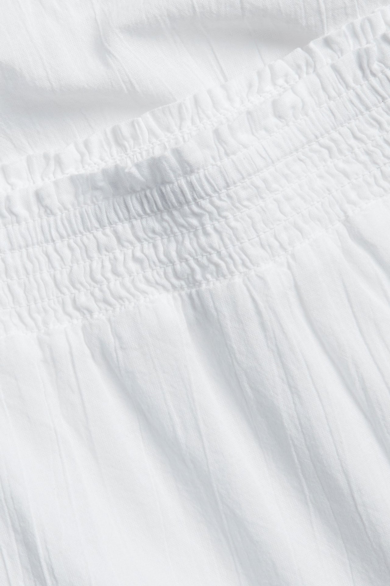 Zbliżenie białej wzorzystej spódnicy maxi ze ściągaczem w pasie z miękkiej tkanej bawełny.