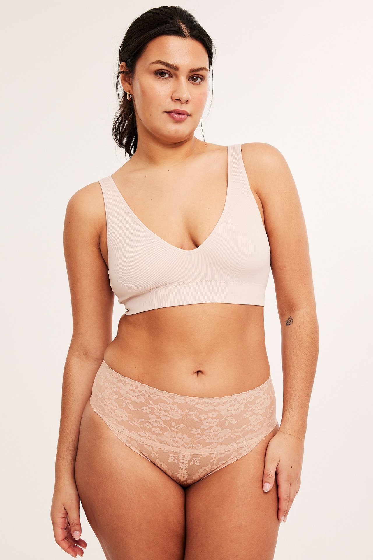 Forfra, kvinne i lyserosa blonde brazilian shapingtruse og en lyserosa ribbet bralette.