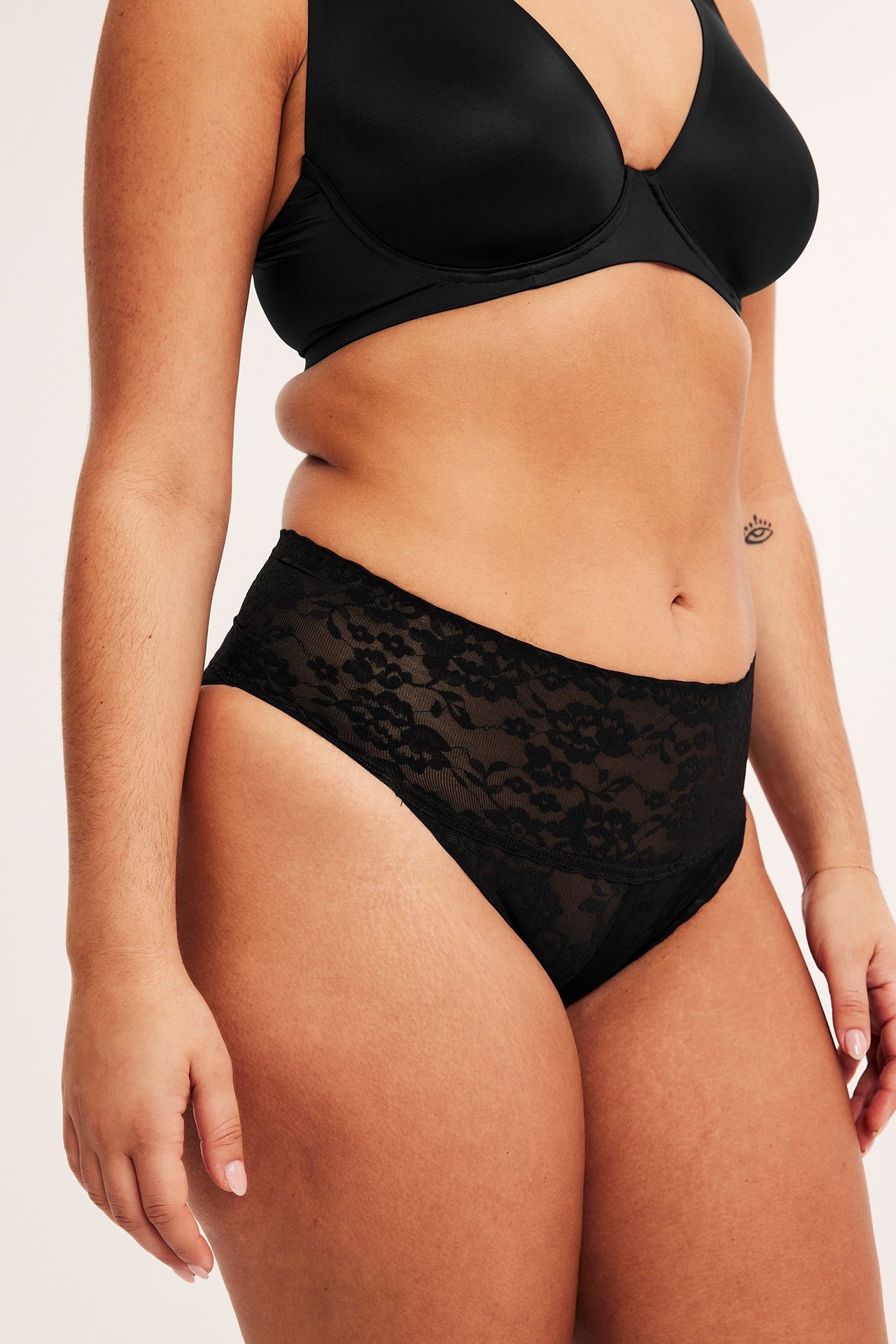 Närbild av kvinna i svarta shaping brazilian trosor i spets och en svart BH.