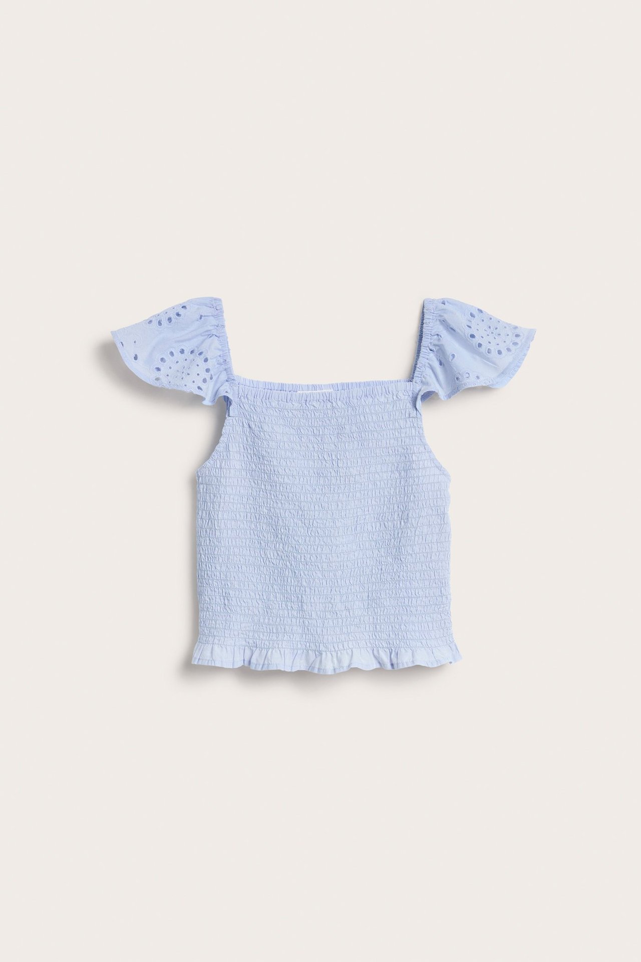 Widok z przodu: jasnoniebieski, marszczony bawełniany top dziecięcy z rękawami broderie anglaise i falbanką.