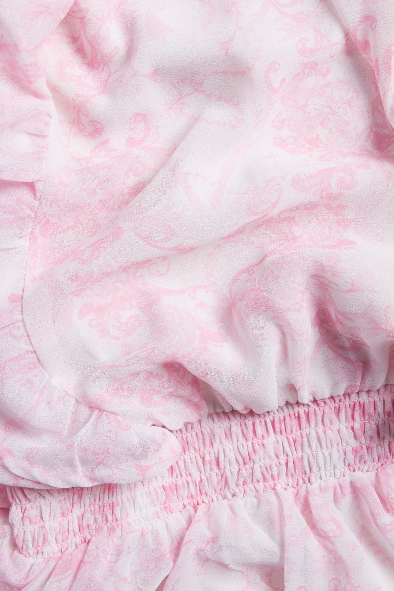 Zbliżenie różowej wzorzystej sukienki szyfonowej z falbanami i marszczonym ściągaczem.