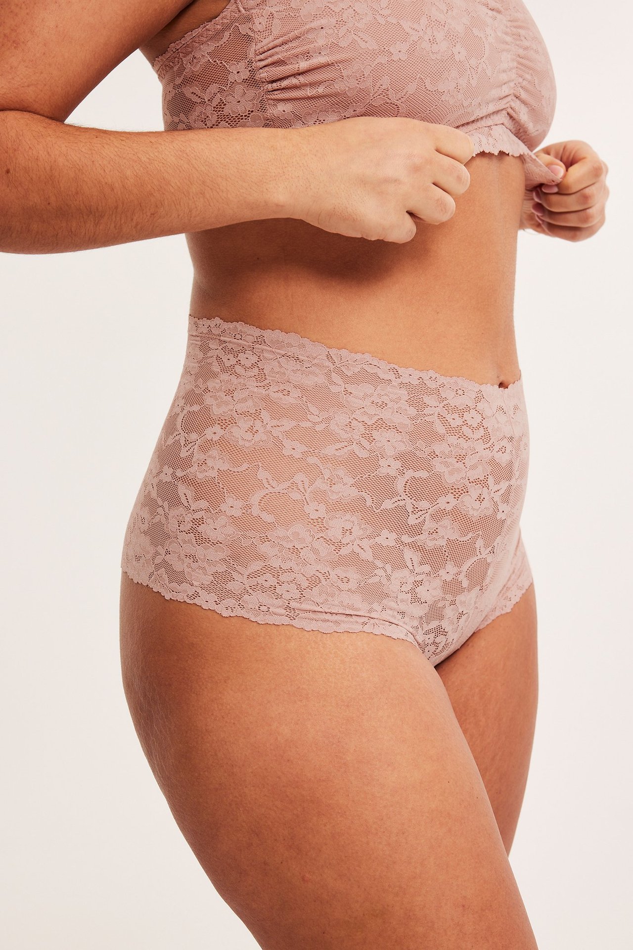 Sidebilde av en kvinne i lys rosa blonde cheeky truse med normal midje og matchende blonde bralette.