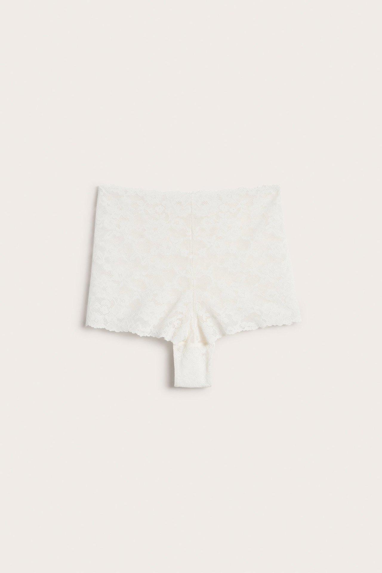 Forfra, offwhite blonde-cheeky-truse med normal midje og bølgete kanter.