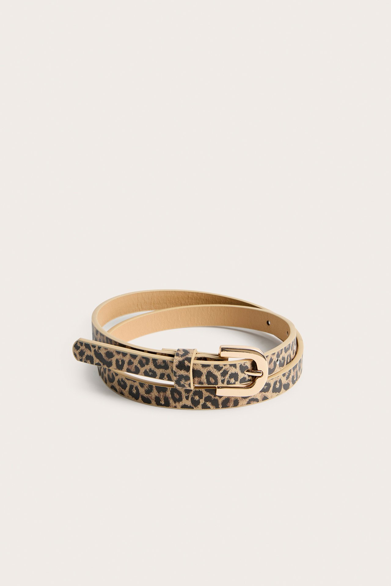 Framifrån, ett brunt leopardmönstrat bälte i polyuretan med guldfärgat spänne, lindat på yta.
