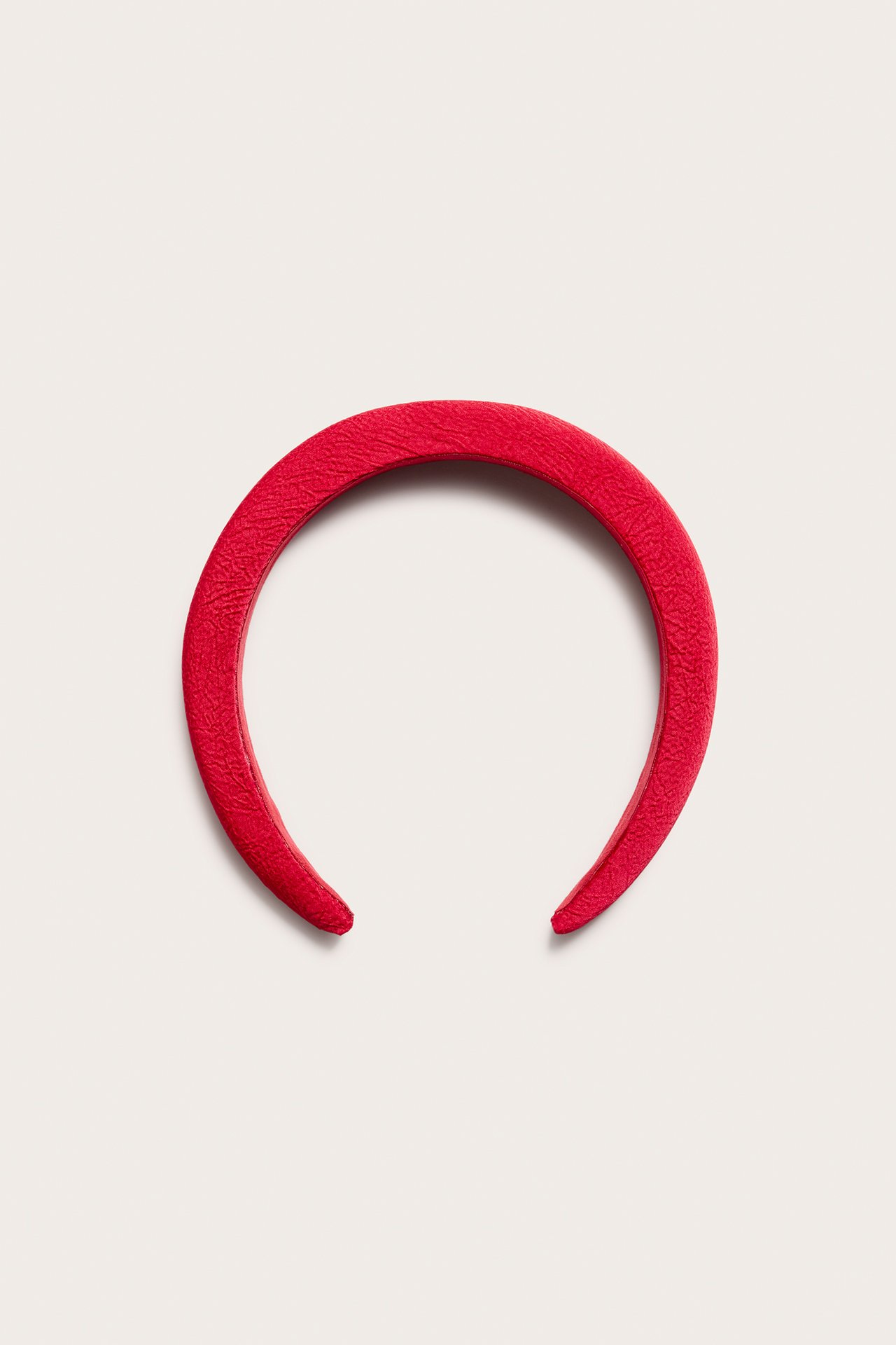 Framifrån, ett rött strukturerat diadem i plast och polyester.