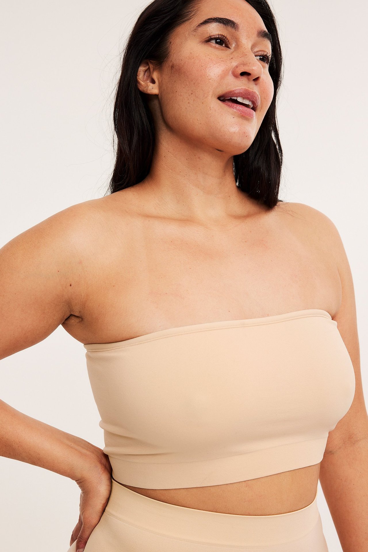 Widok z przodu: kobieta w beżowym bezszwowym biustonoszu bandeau i pasujących majtkach z wysokim stanem.