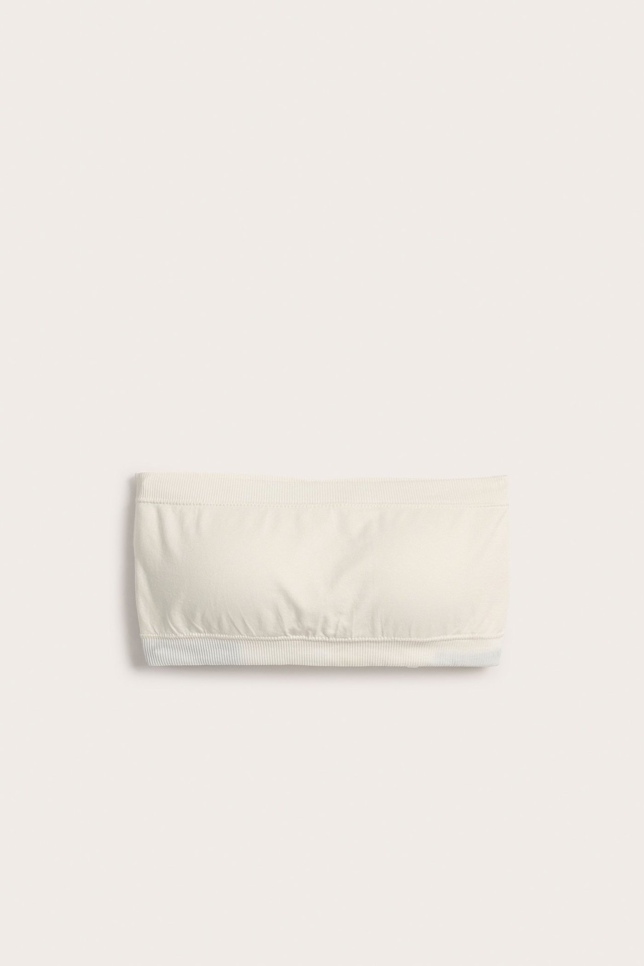 Edestä, valkoinen saumaton kaaritueton bandeau-rintaliivi ribbireunoilla.