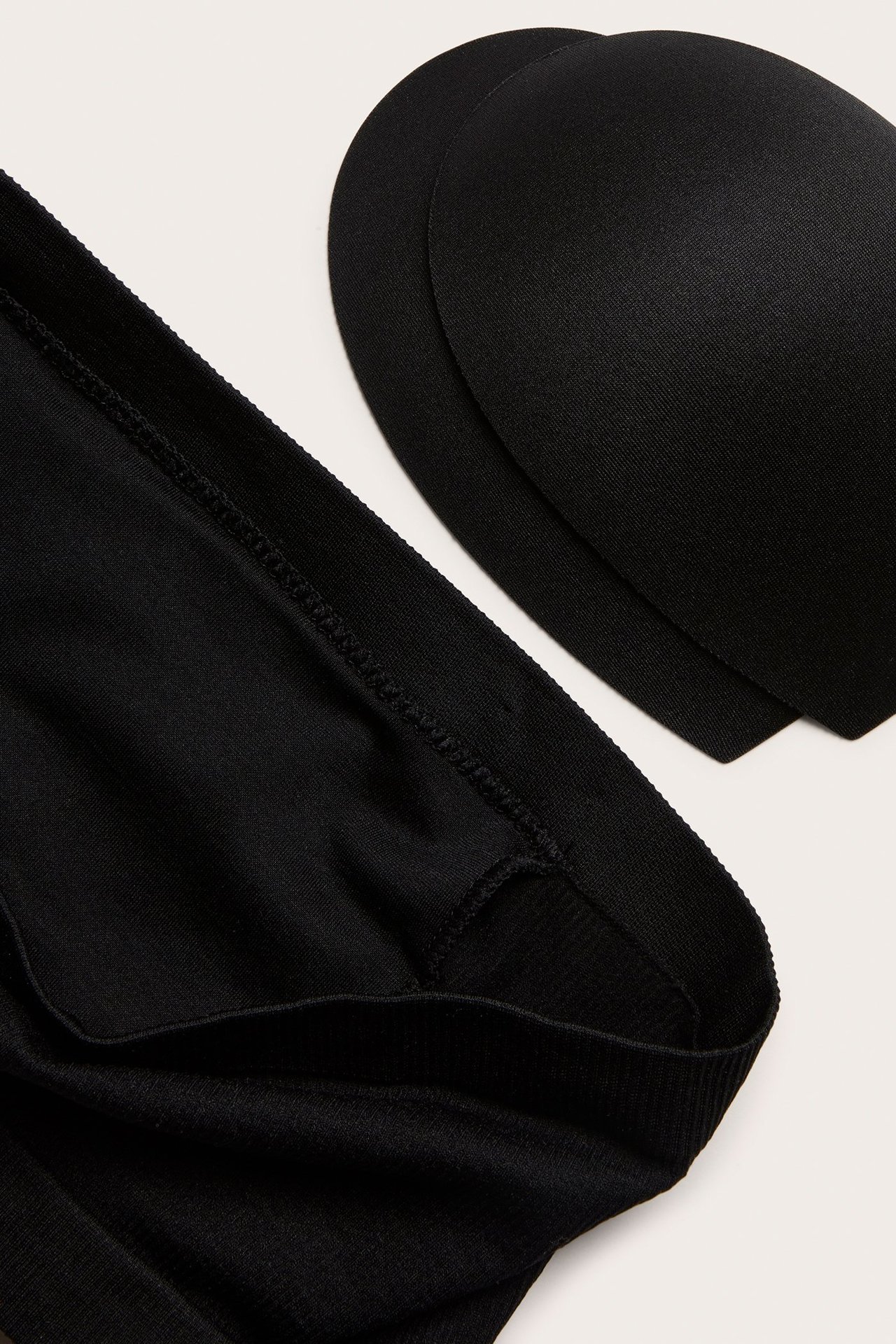 Zbliżenie czarnego, bezszwowego biustonosza bandeau z dwoma czarnymi, wyjmowanymi wkładkami.