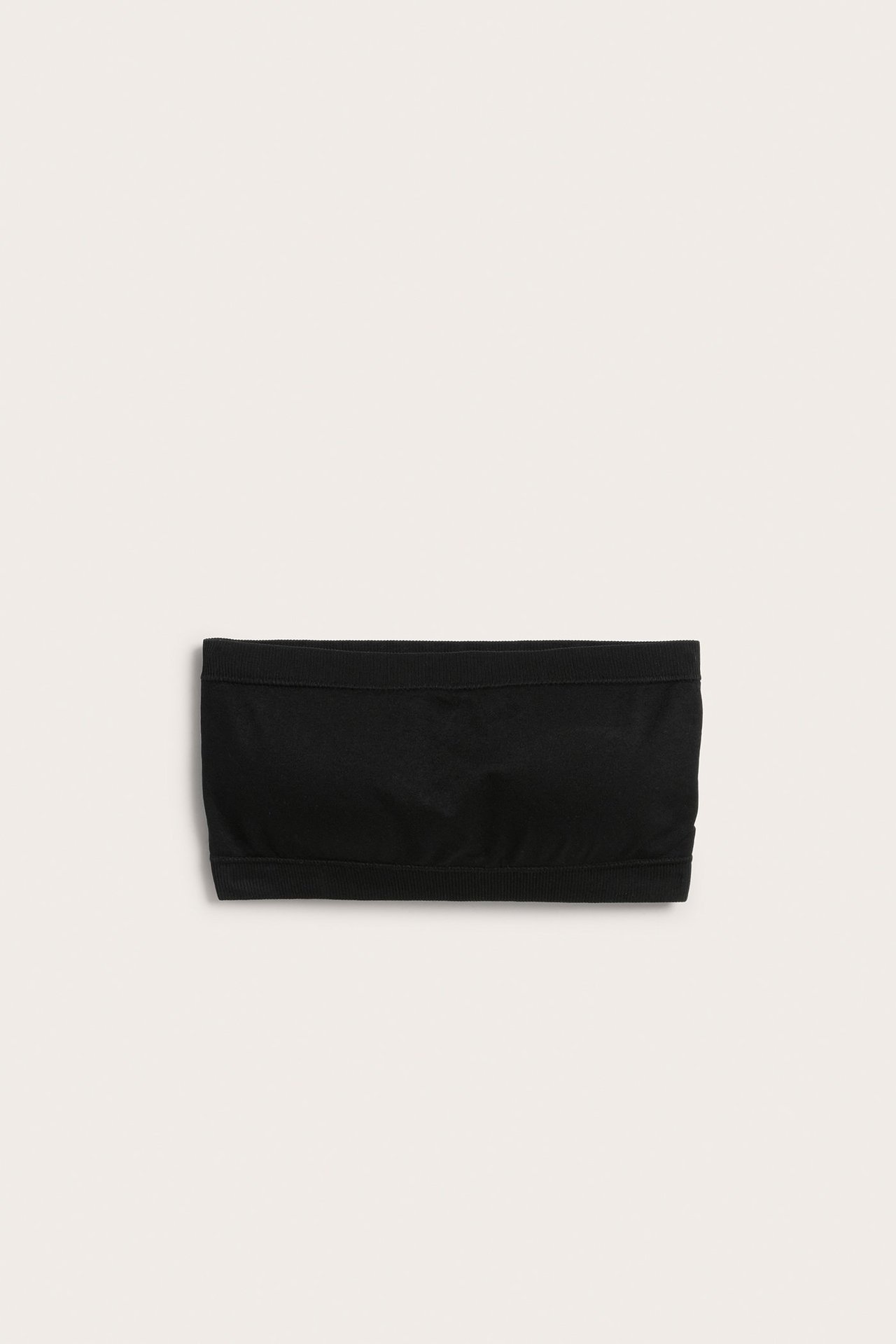 Frontvisning av en svart sømløs bandeau-bh med elastiske kanter, laget av glatt stoff.
