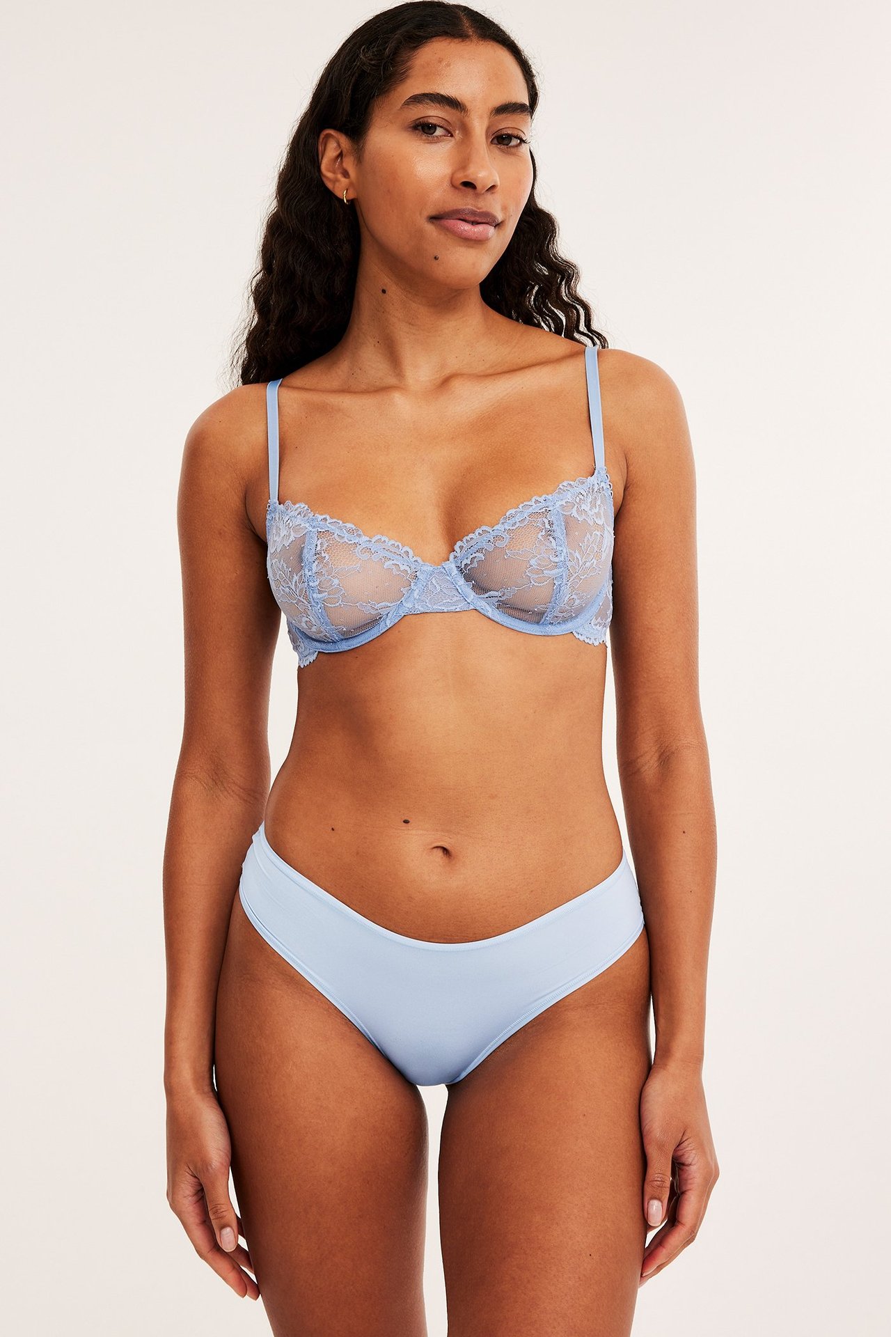 Forfra, kvinne i lyseblå brazilian-truse og matchende gjennomsiktig blonde-bh.