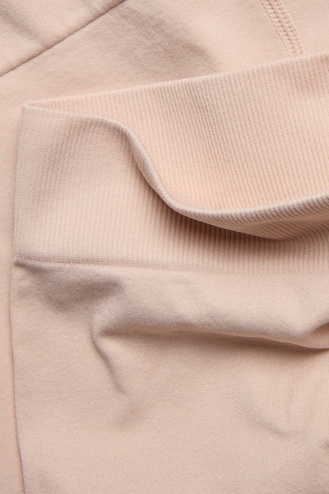 Zbliżenie na jasnoróżowe bezszwowe szorty z prążkowanym detalem.