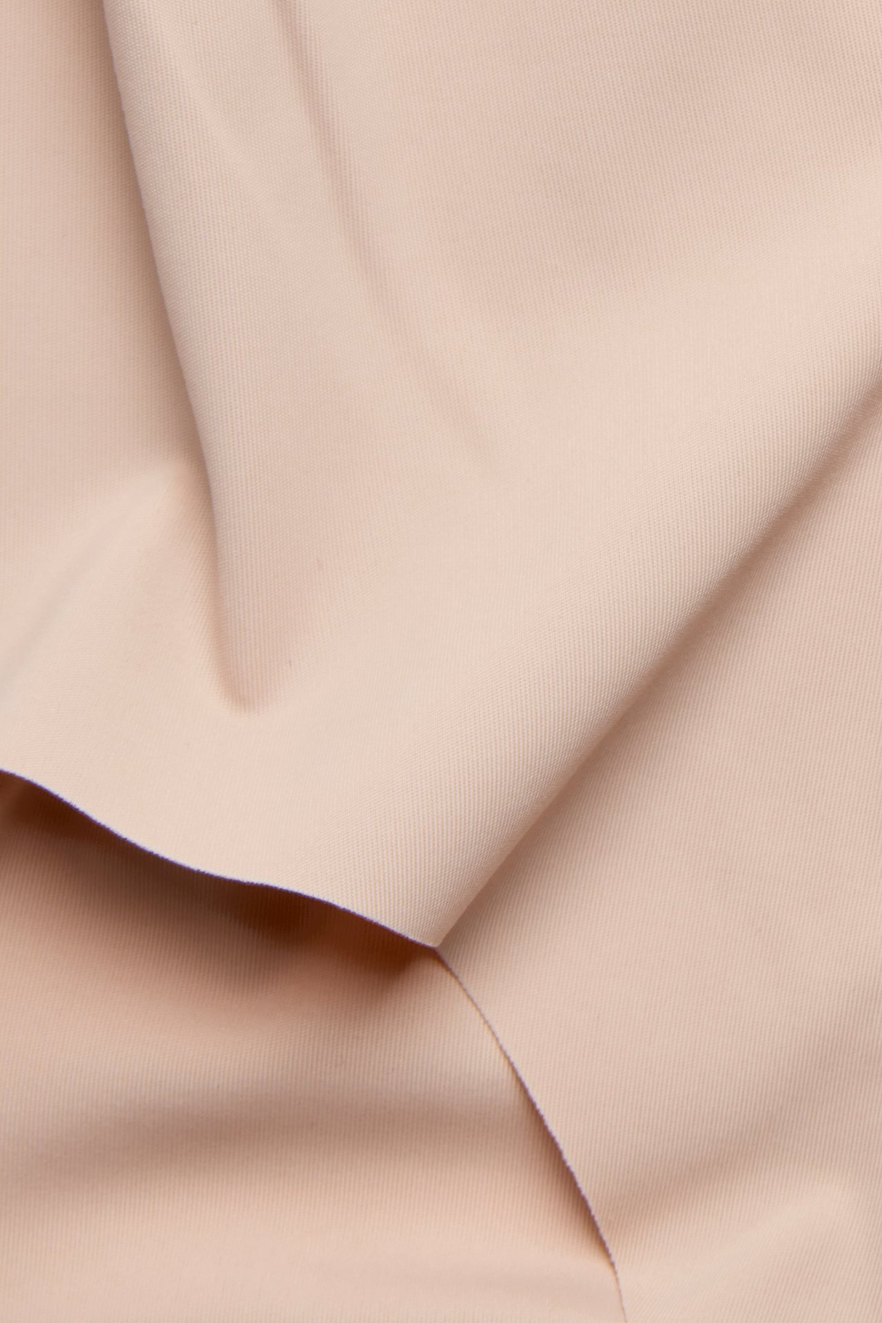 Zbliżenie jasnoróżowego, gładkiego, jednolitego materiału, prawdopodobnie na stringi clean-cut.