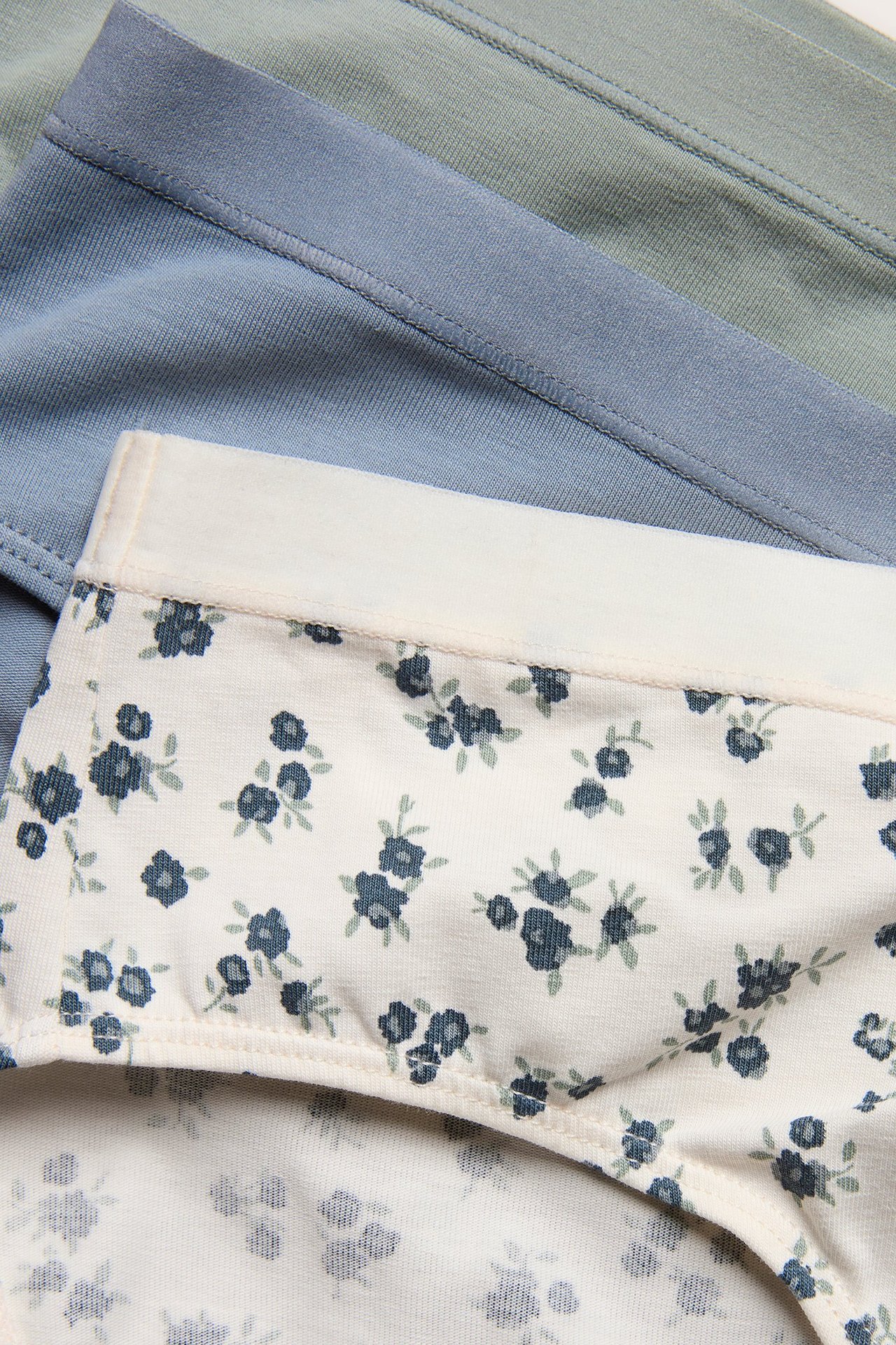 Zbliżenie na białe figi w niebieskie kwiaty, z jasnoniebieskimi i jasnozielonymi figami z tyłu.