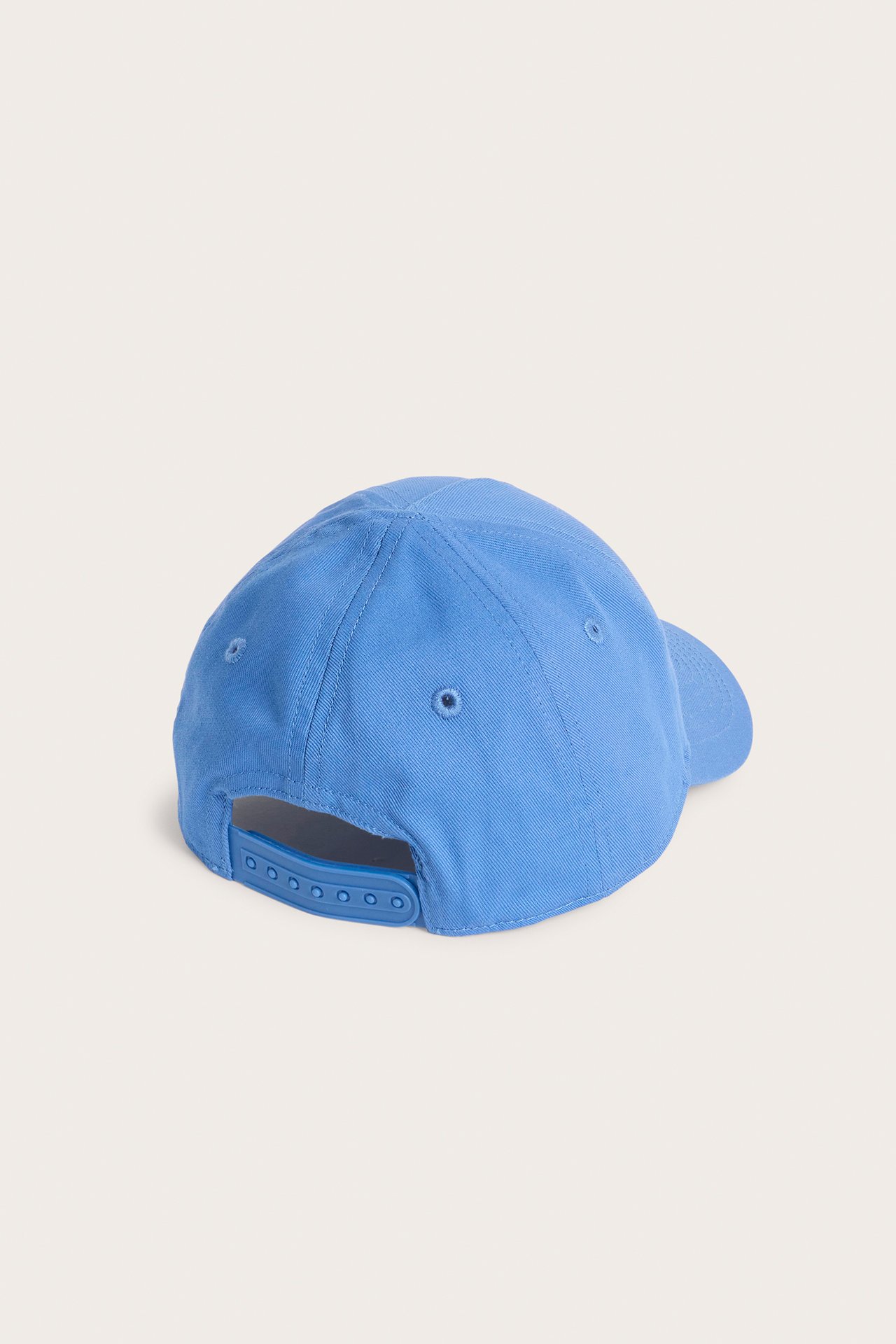 Bakifrån av en blå barnkeps med justerbar snapback-knäppning.