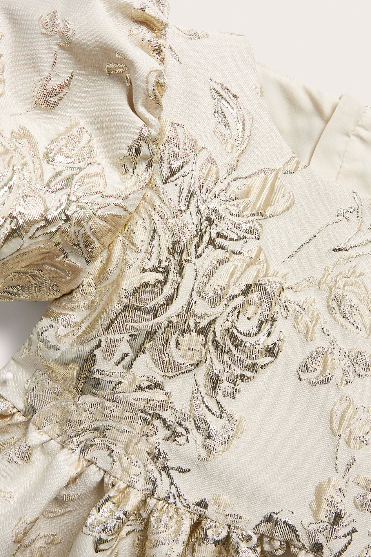 Zbliżenie na złotą brokatową sukienkę żakardową dla dzieci z bufiastymi rękawami.