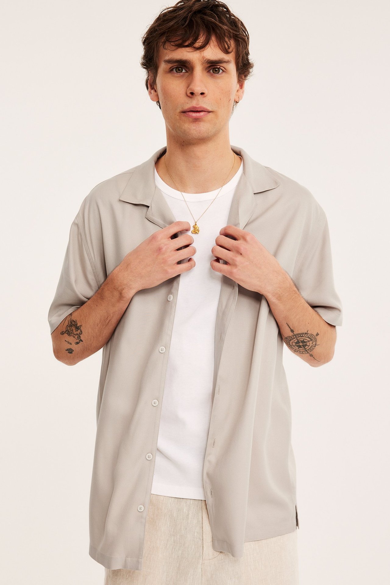 Edestä: Mies yllään avoin vaaleanbeige viskoosipaita valkoisen t-paidan ja vaaleiden housujen kanssa.