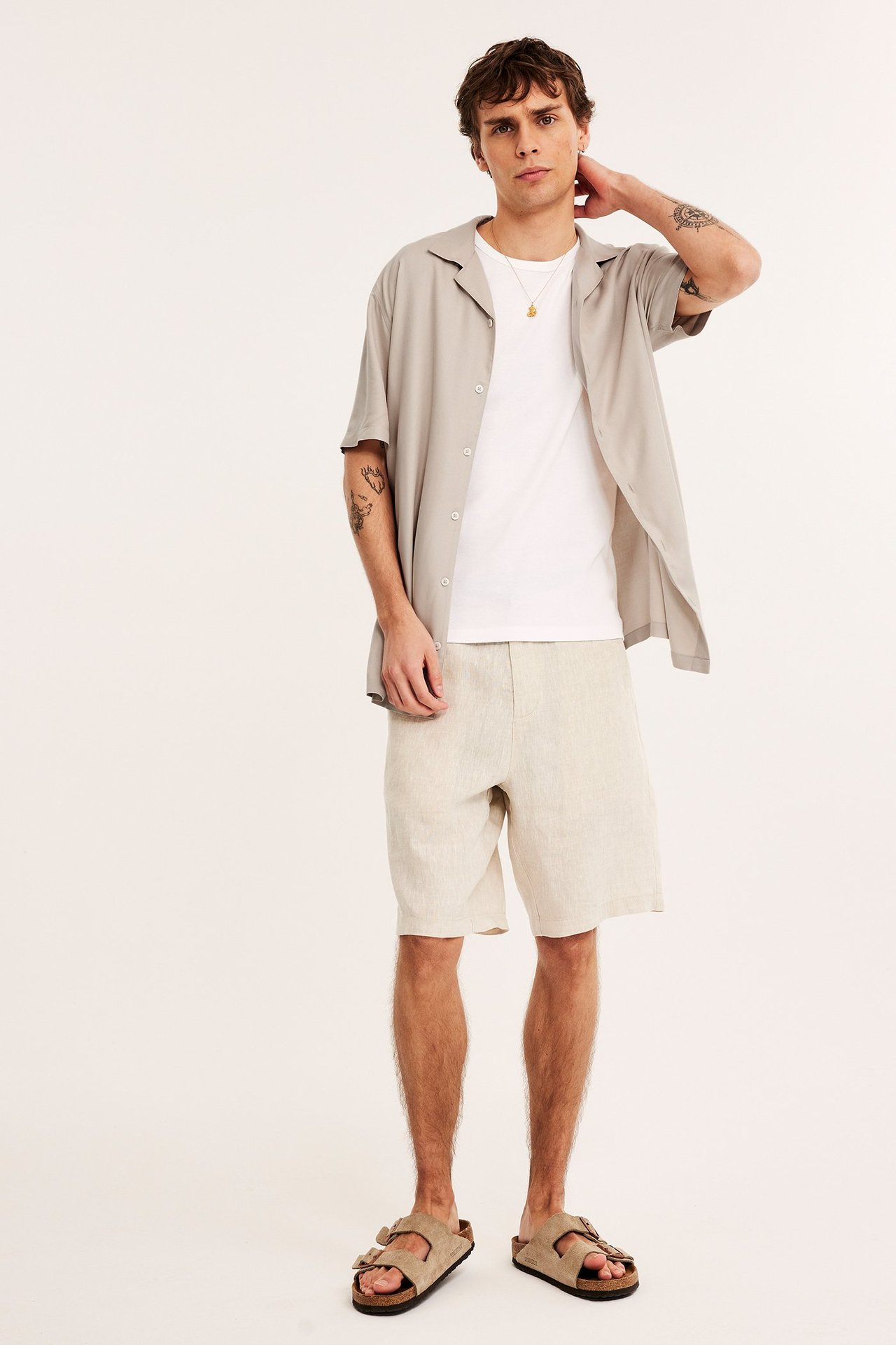 Edestäpäin: Mies yllään vaaleanbeige melange viskoosipaita, valkoinen t-paita, beiget shortsit ja sandaalit.