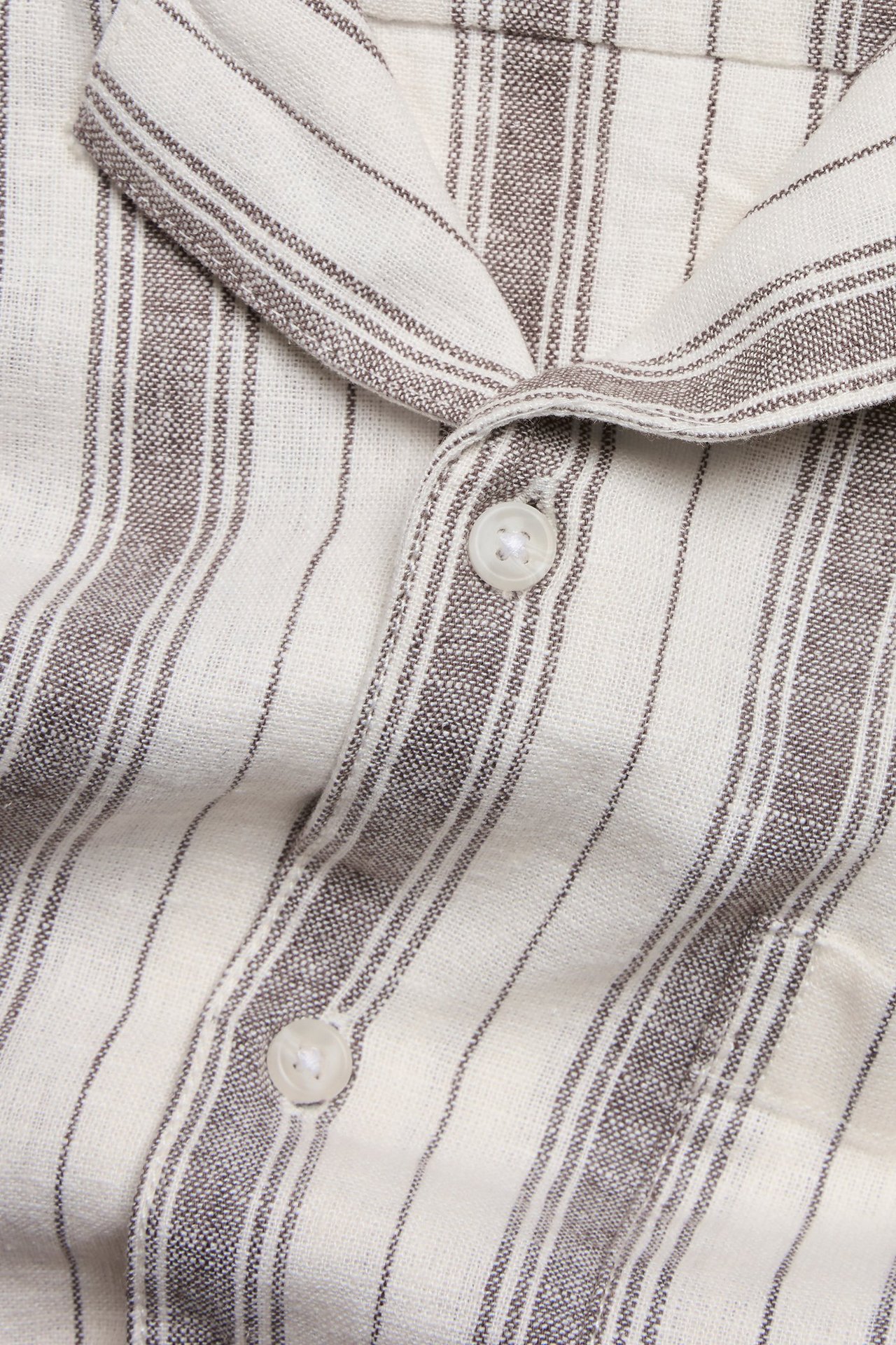 Zbliżenie na brązowo-białą koszulę w paski z krótkim rękawem z mieszanki lnu, z białymi guzikami.