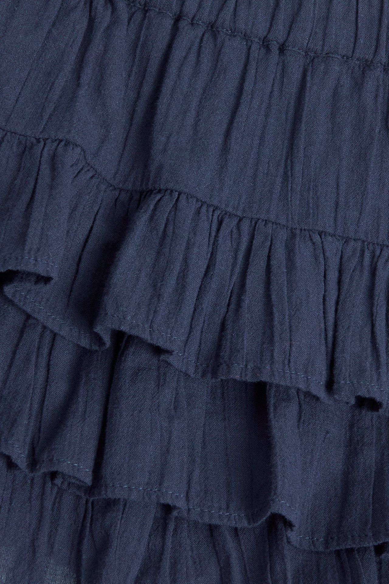 Zbliżenie niebieskiej krótkiej spódnicy z falbanami z tkanej strukturalnej bawełny.