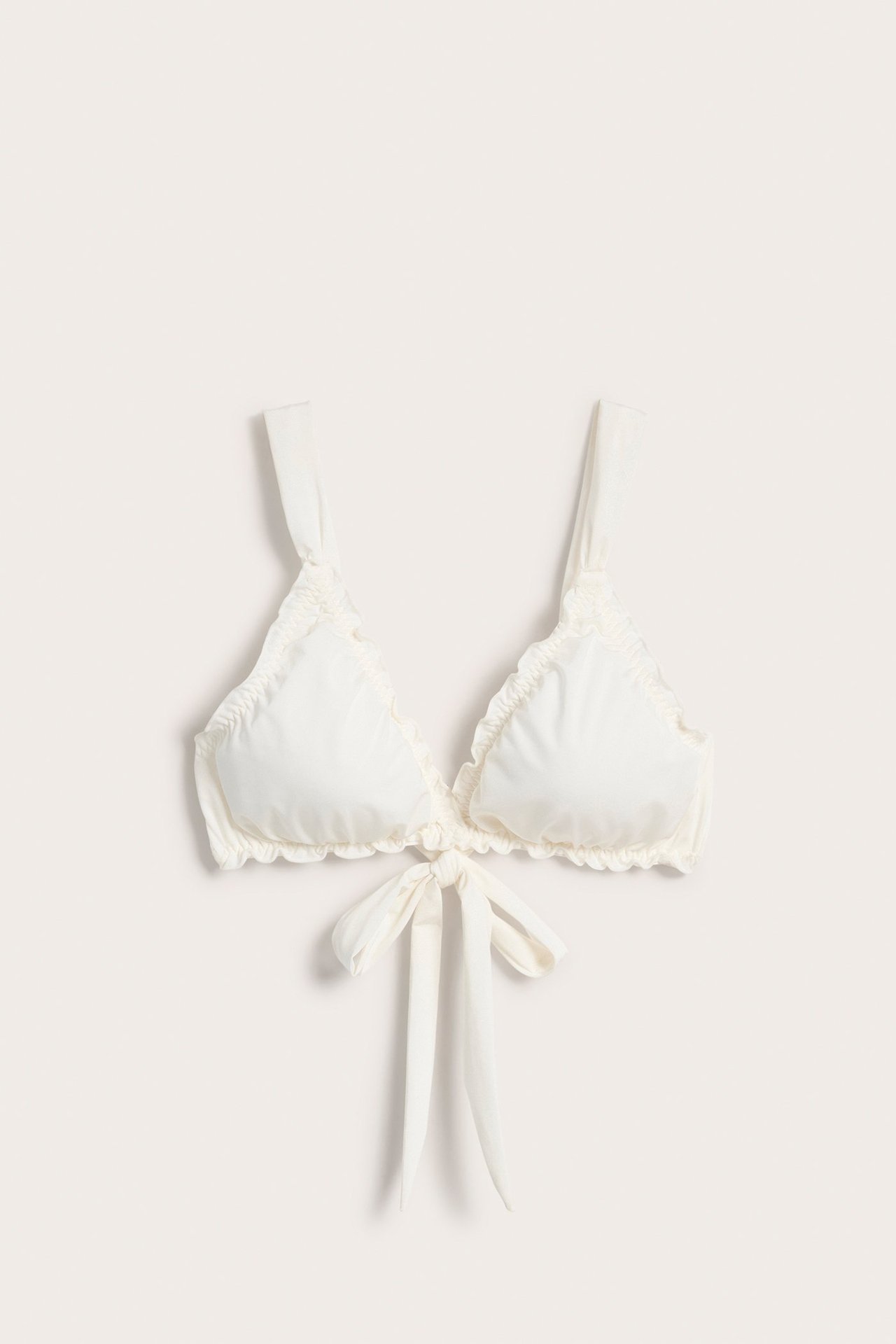 Framifrån: Offwhite bygellös BH-topp med trekantiga kupor, breda rynkade axelband och knytning fram.