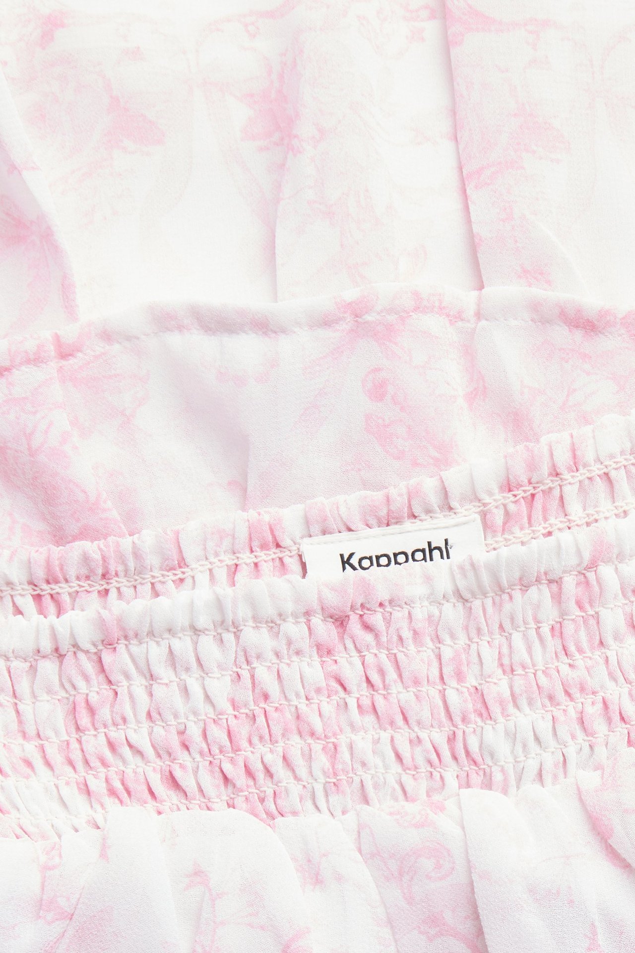 Zbliżenie różowej wzorzystej krótkiej spódnicy z szyfonu z falbanami i marszczonym pasem.