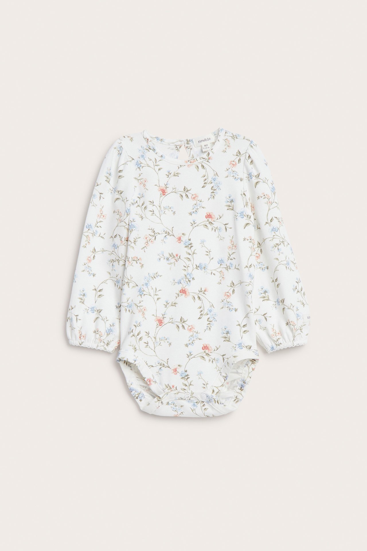 Framifrån, offwhite babybody i jersey med långa puffärmar och ett delikat blommigt mönster.