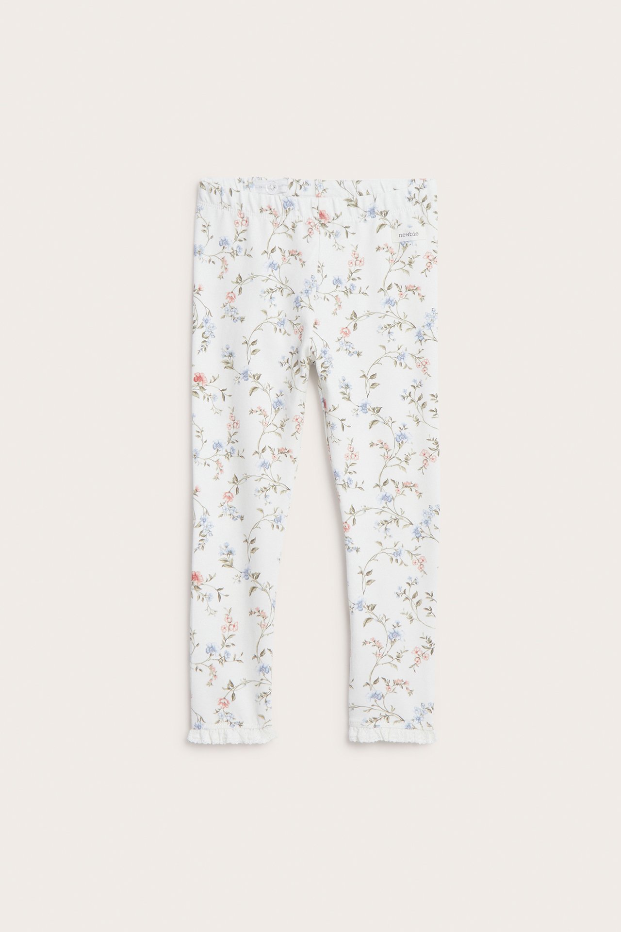 Framifrån: Barnens offwhite blommiga leggings med små blå, rosa blommor och spetskant.