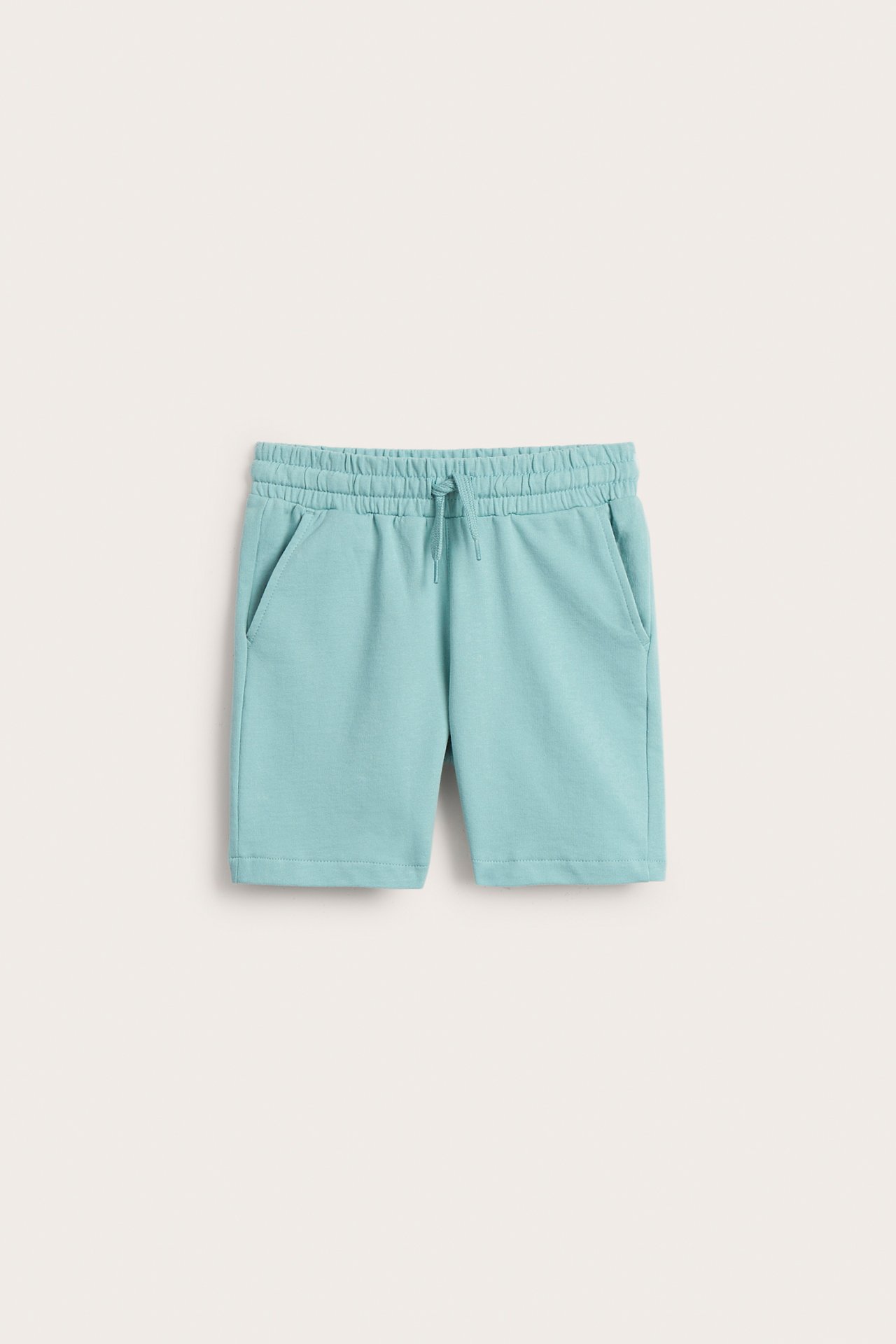 Frontvy av ljusgröna bomullsshorts för barn med resårlinning, dragsko och sidfickor.
