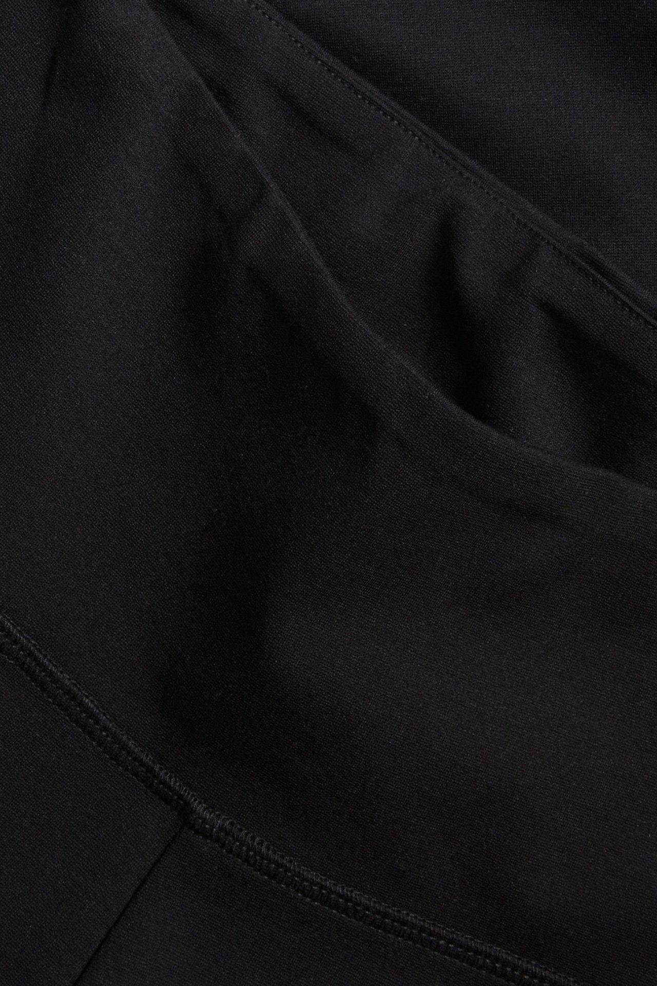 Zbliżenie czarnych, jednolitych kolarek z dzianiny, z widocznymi szwami i zagnieceniami materiału.