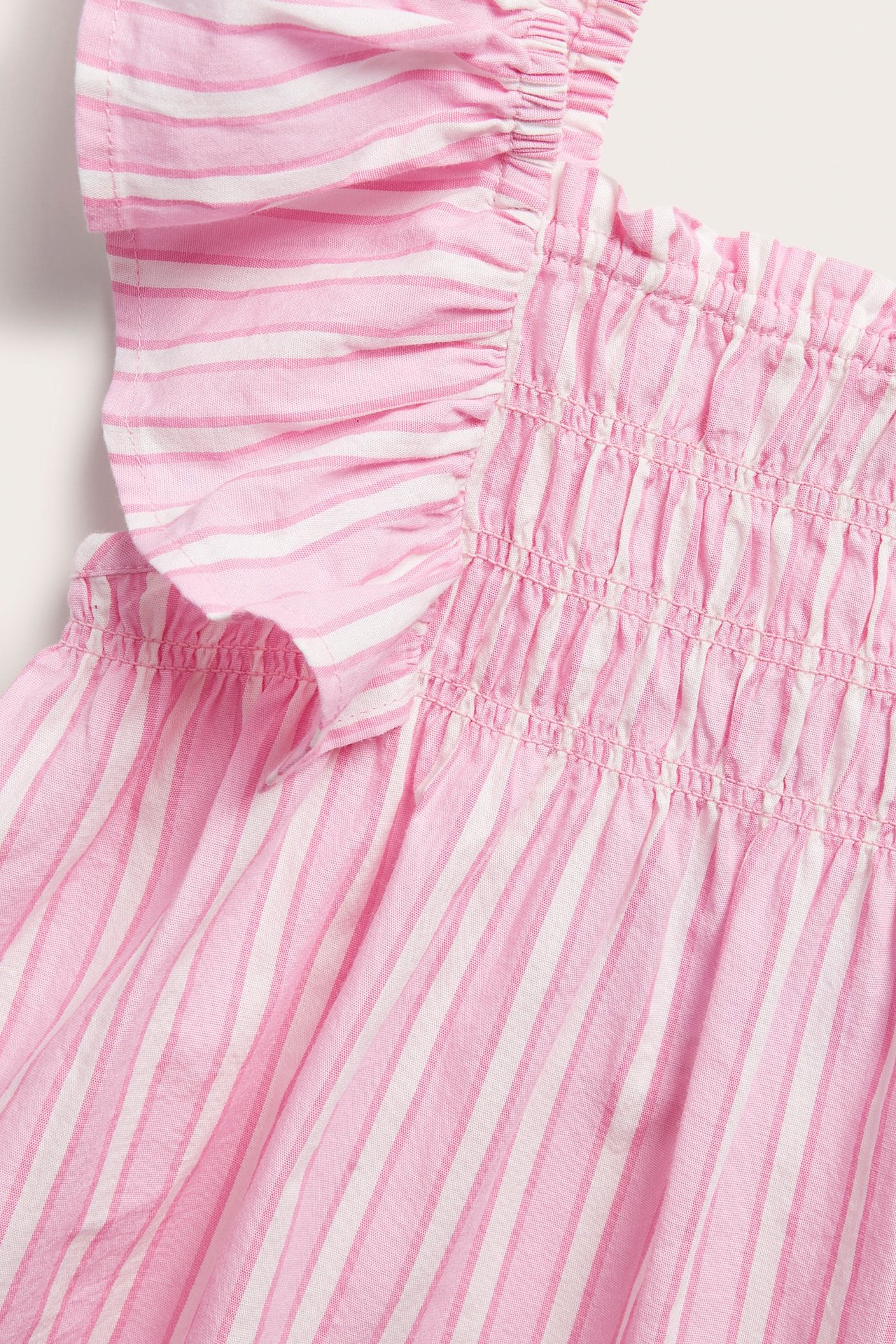 Zbliżenie różowo-białej bawełnianej bluzki w paski z falbankami i marszczeniami.