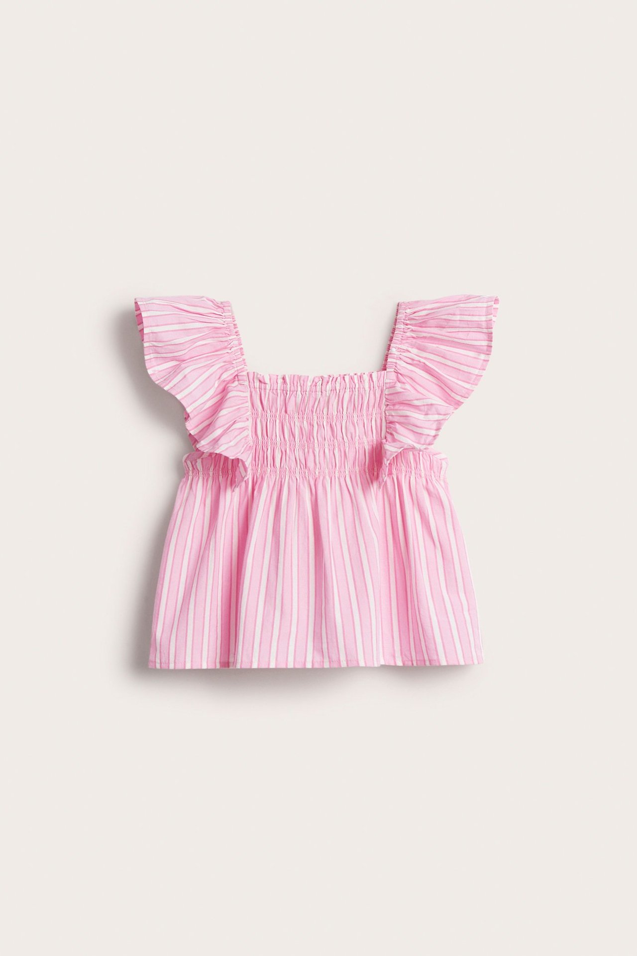 Widok z przodu różowo-białego, pasiasto-falbaniastego topu dziecięcego z bawełny ze ściągaczem.