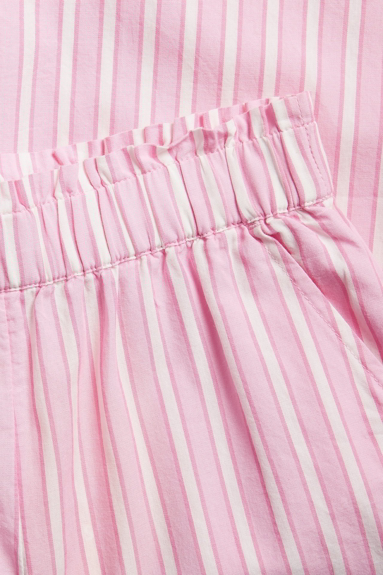 Zbliżenie na różowo-białe bawełniane spodnie culotte w paski z elastyczną talią i boczną kieszenią.