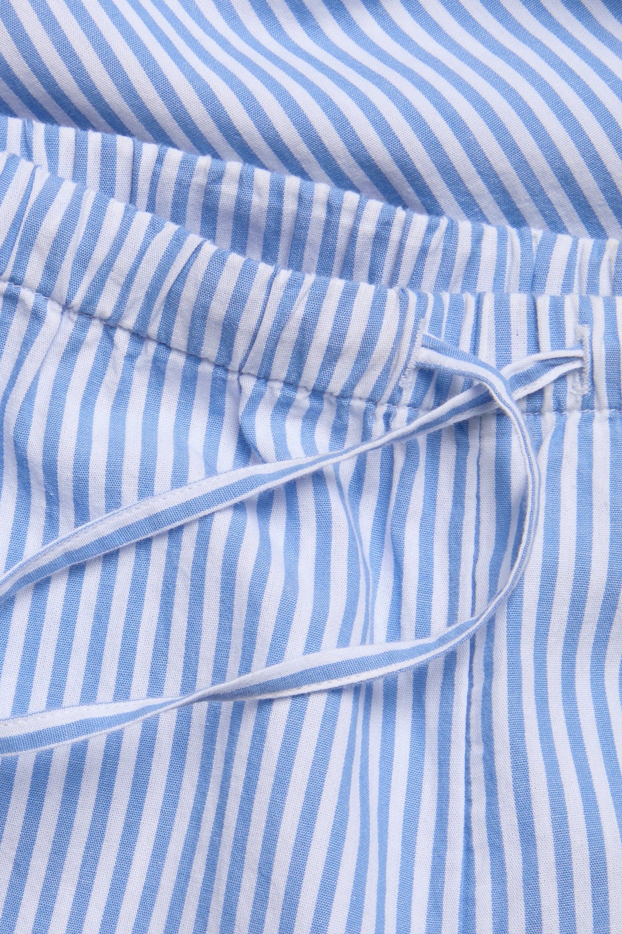 Zbliżenie niebiesko-białych bawełnianych spodni w paski z elastycznym pasem i sznurkiem.