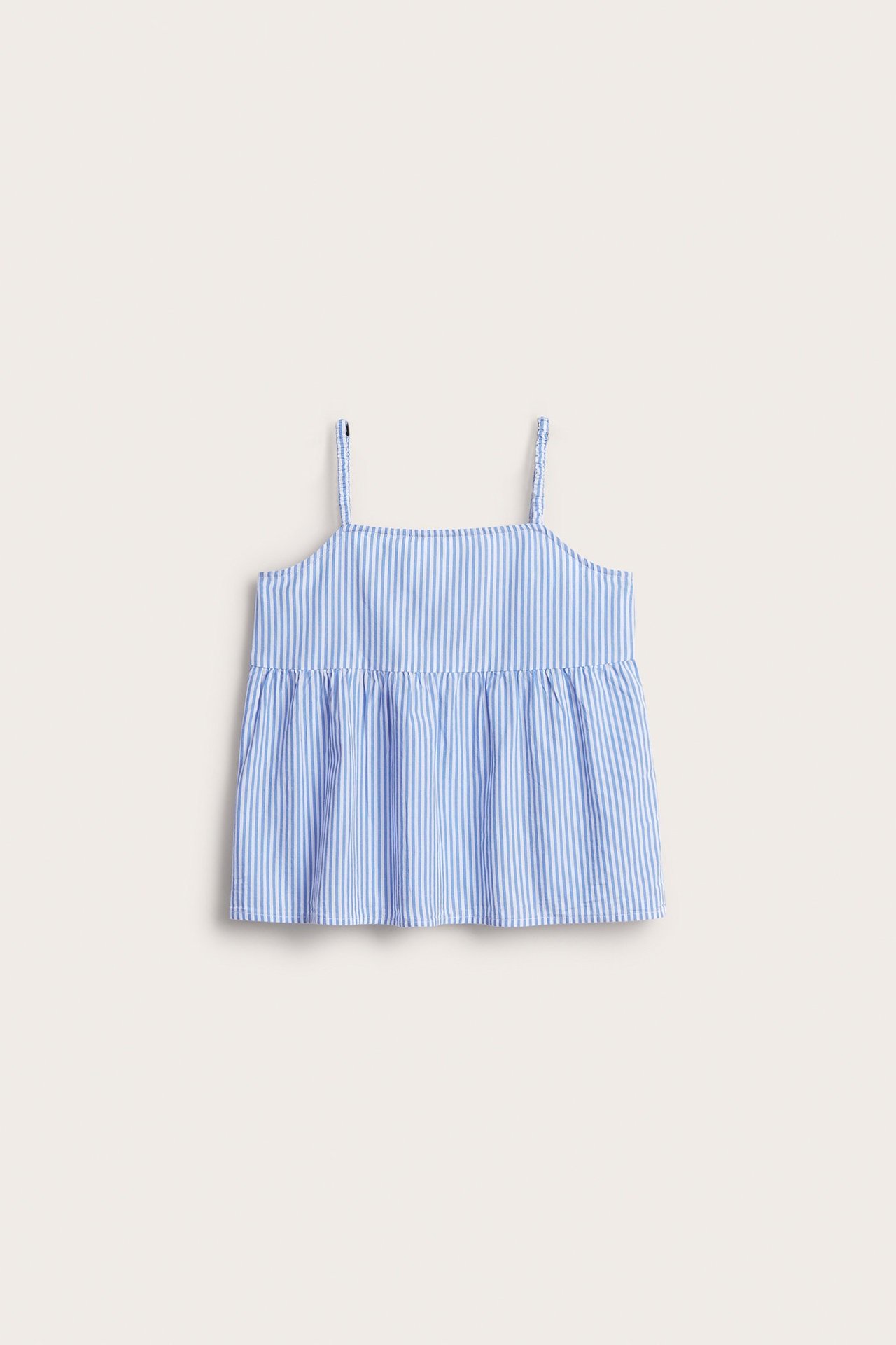 Frontvy av en randig blåvit blustopp i strukturerad bomull med tunna axelband för barn.