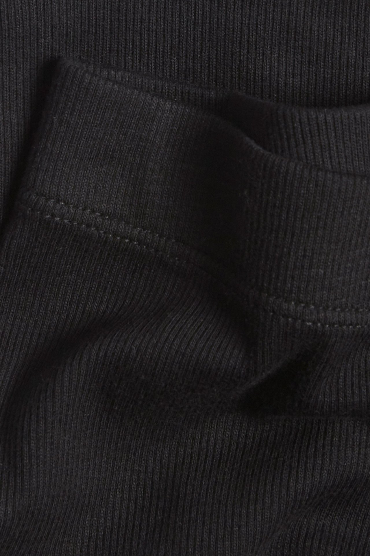 Zbliżenie czarnych prążkowanych szortów rowerowych, ukazujące fakturę materiału i szew.