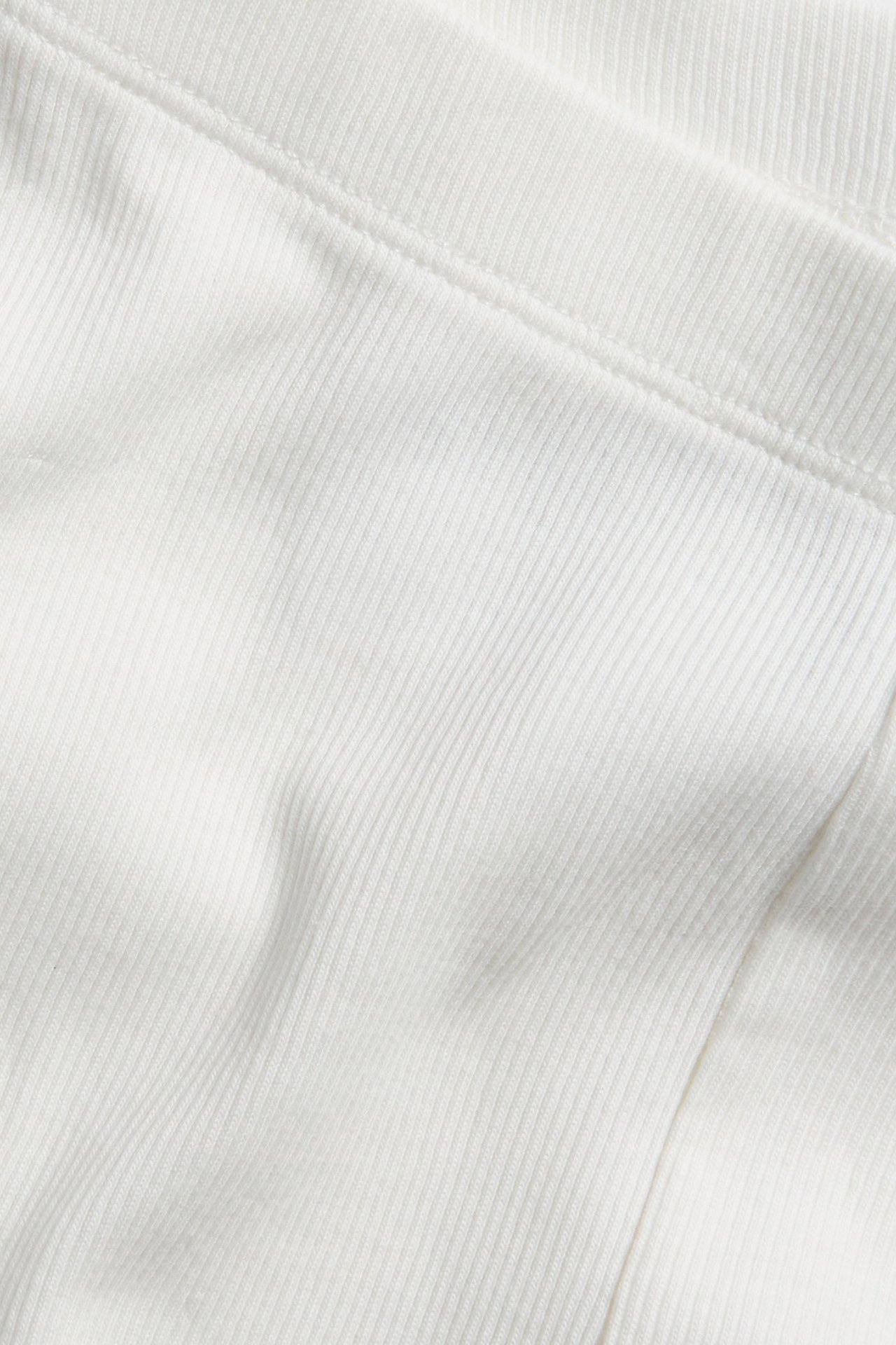 Zbliżenie białych, prążkowanych legginsów rowerowych, ukazujące fakturę materiału i szew.