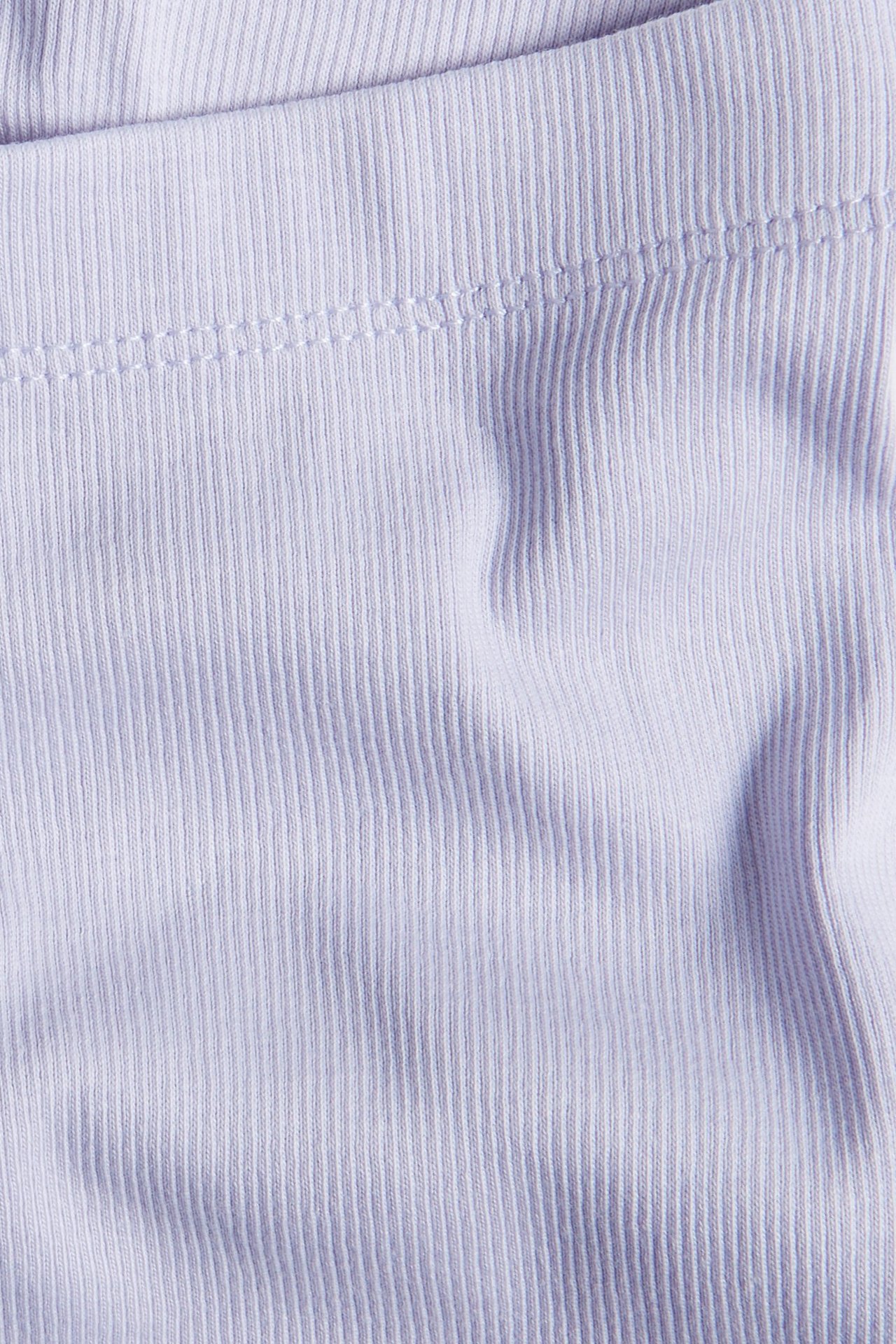 Zbliżenie na liliowy prążkowany materiał kolarek, ukazujące pionowy wzór w prążki i szwy.