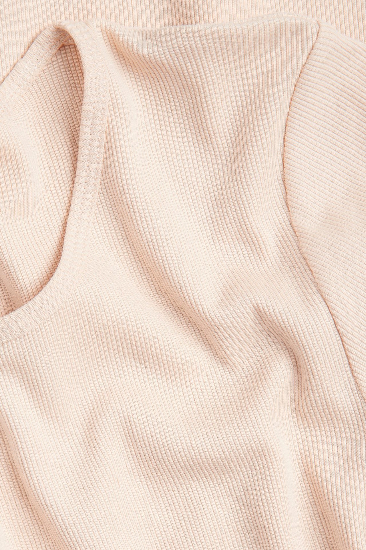 Zbliżenie jasnoróżowego prążkowanego, dopasowanego T-shirtu o wąskiej strukturze.