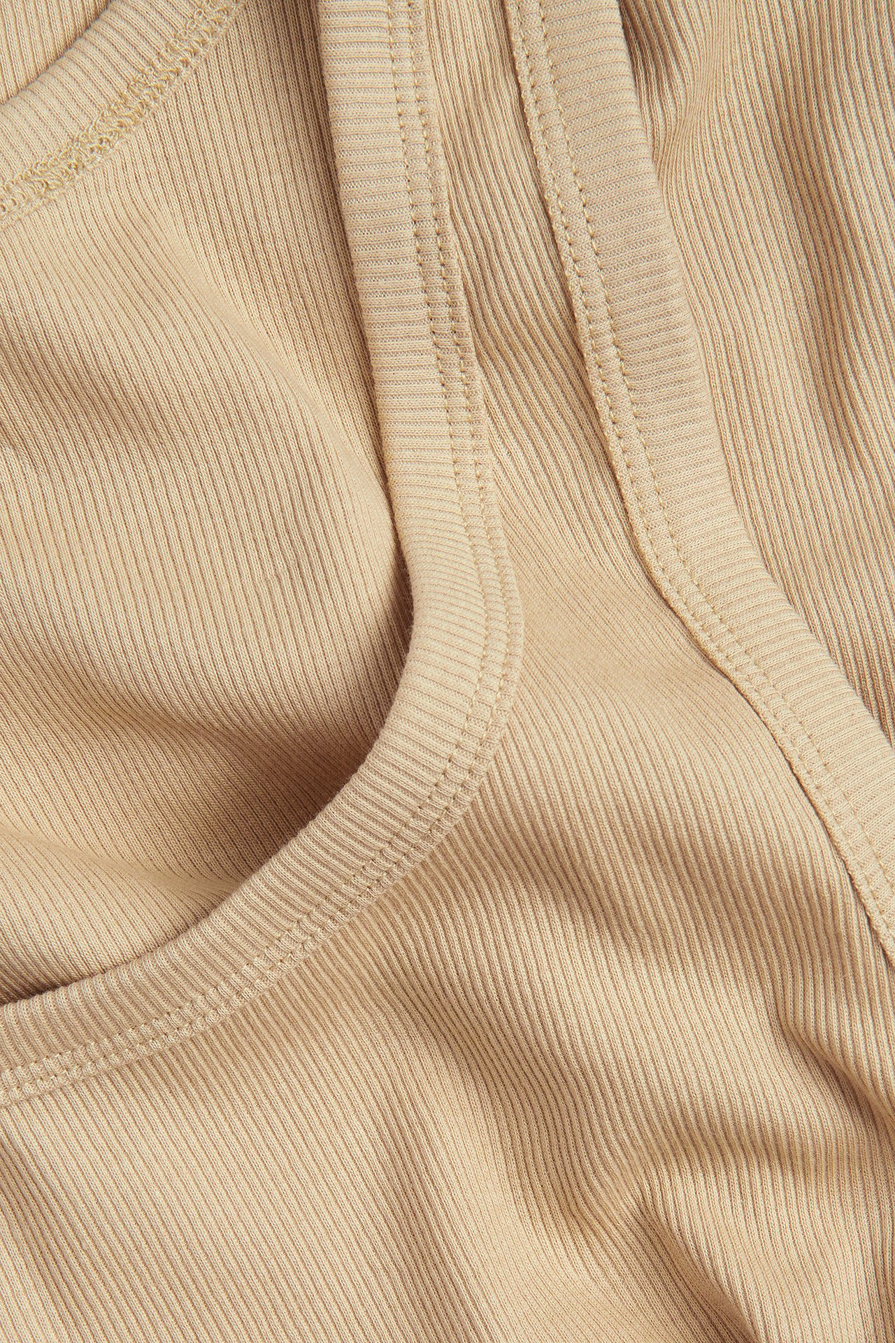 Närbild på ett beige ribbat linne, som visar dess smala ribbstruktur och avslutade kanter.